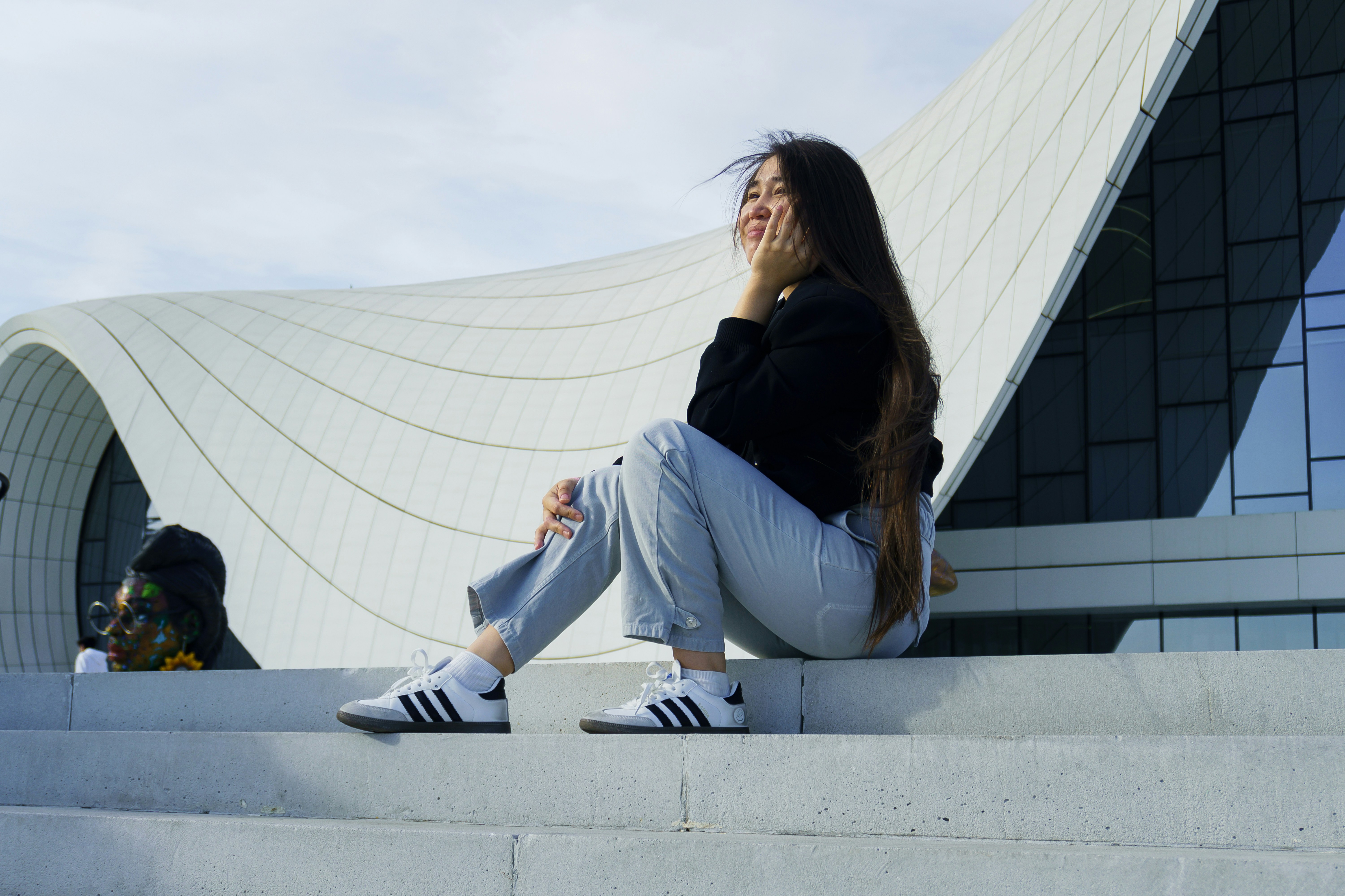 Young woman sitting on steps near modern building