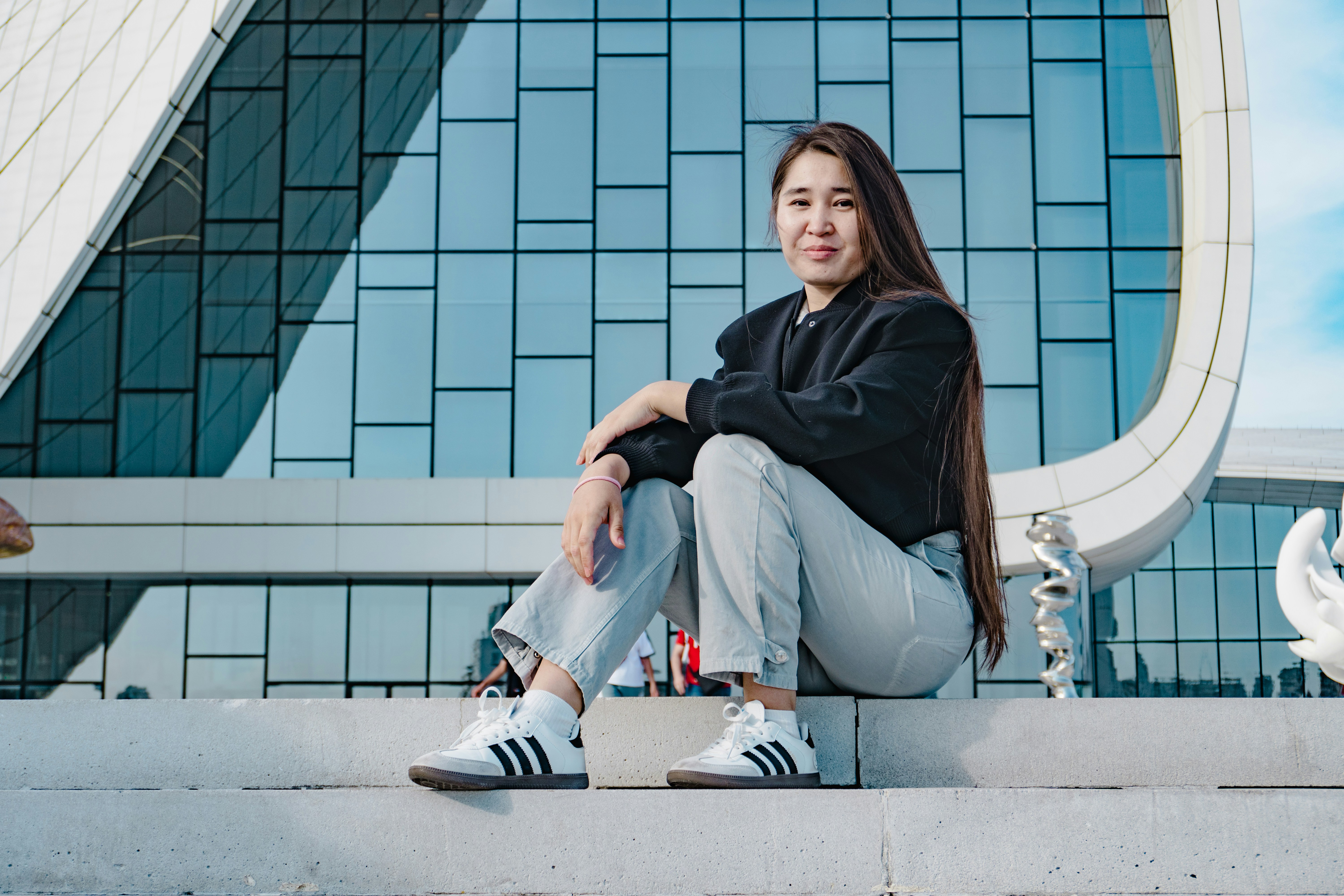 Young woman sitting in front of modern building