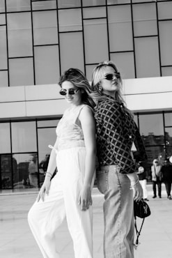 Two stylish women posing back to back outdoors