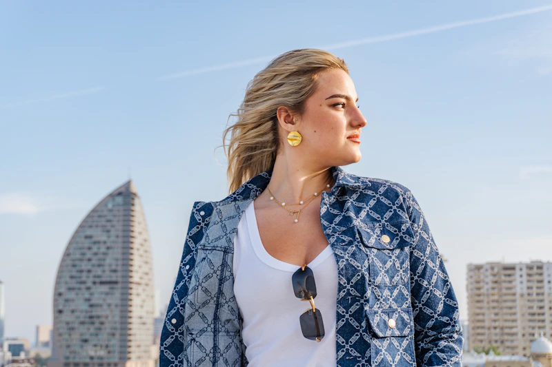 Woman in denim jacket looking away outdoors.