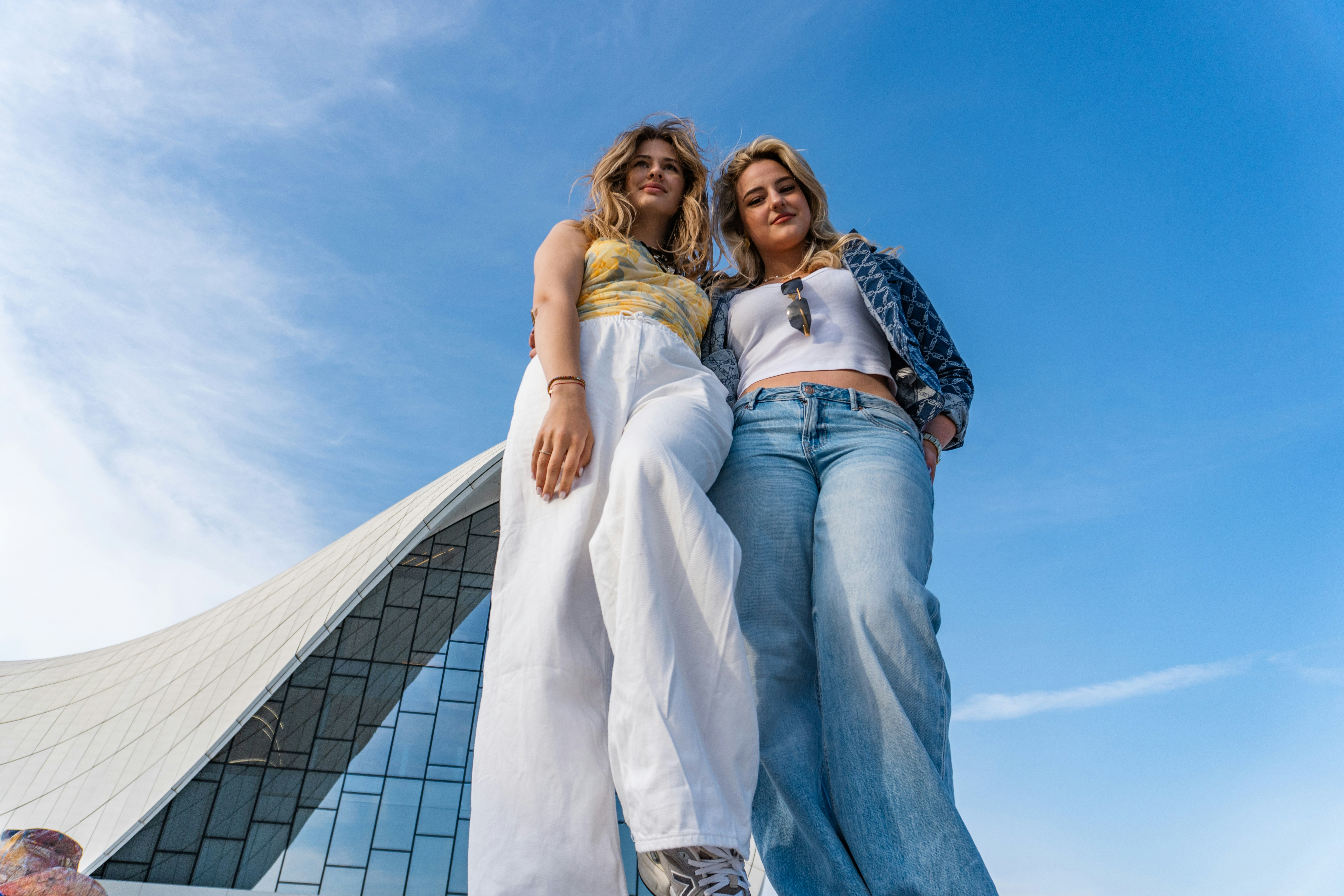Two women standing against a blue sky.