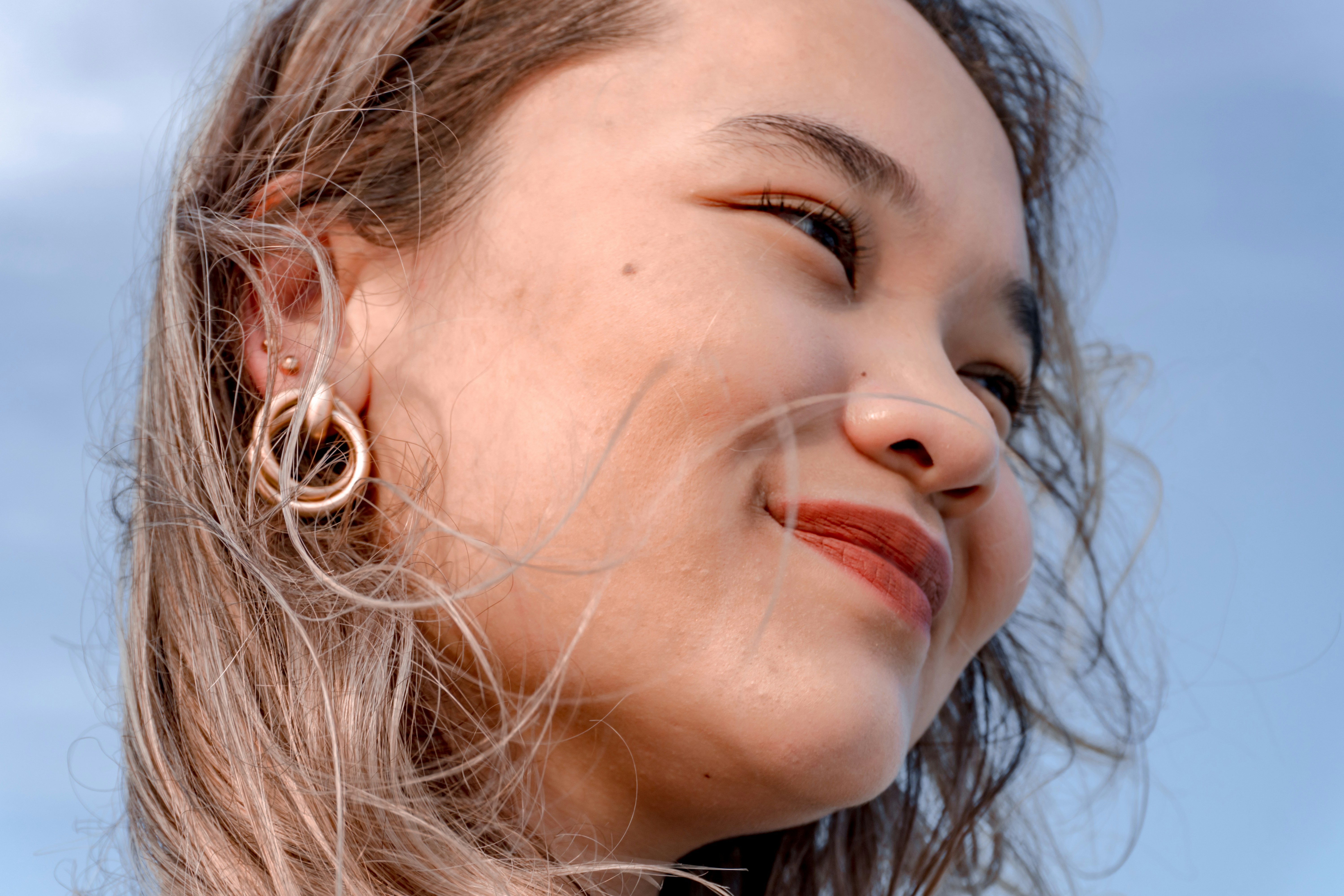 Young woman with blonde hair and hoop earrings smiles.