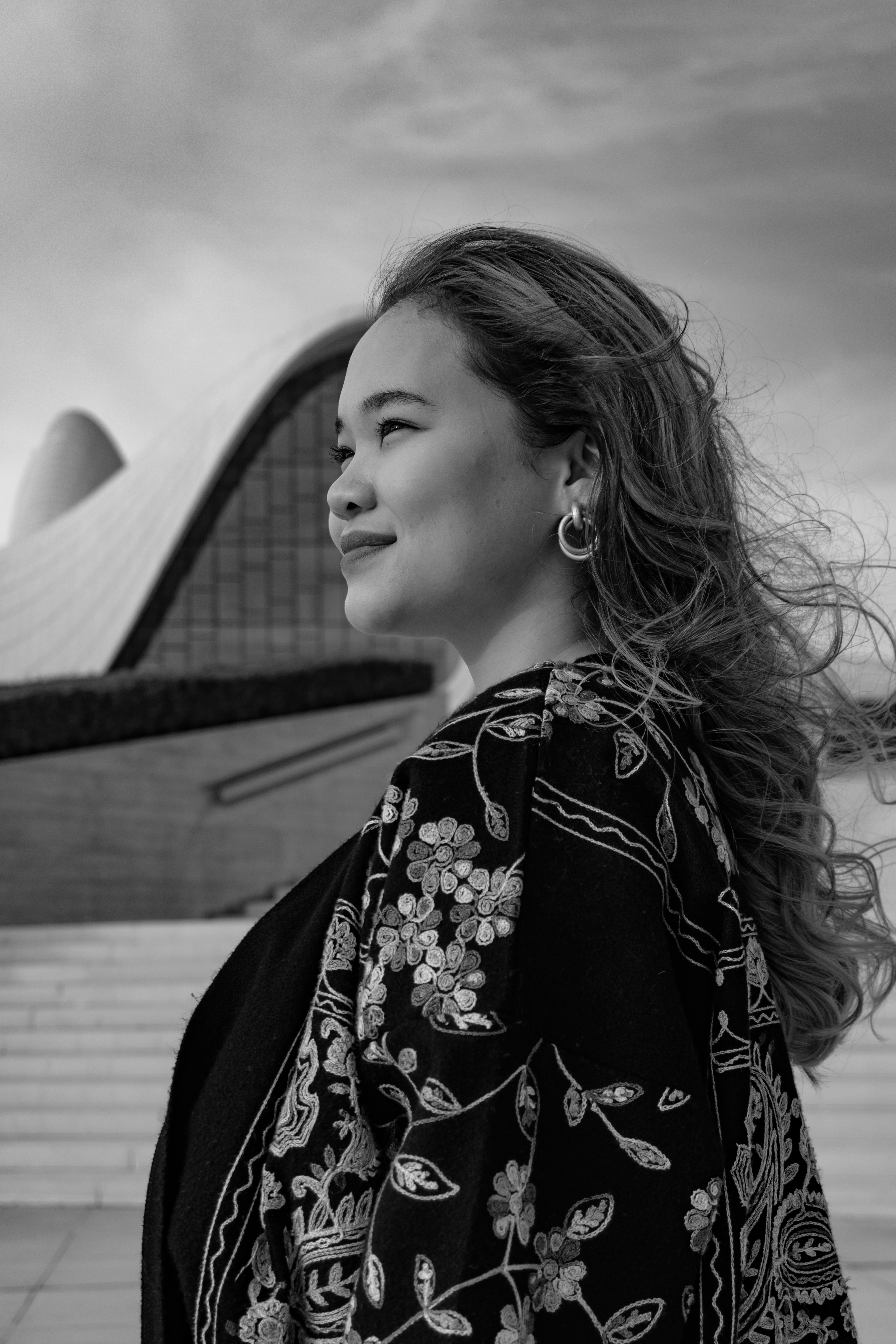 現代建築を背景に模様のショールを着た若い女性