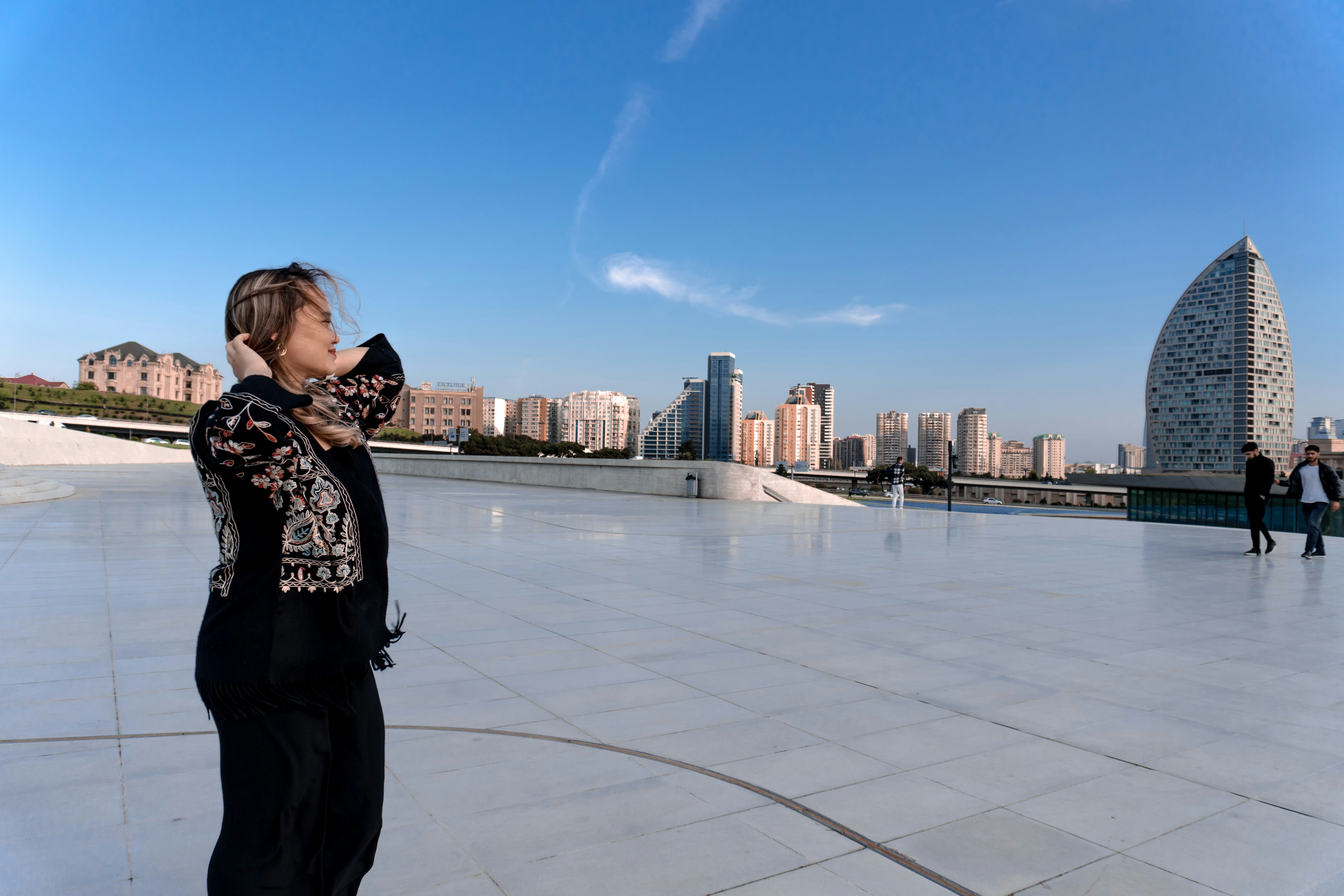 Woman with headphones on a rooftop overlooking city skyline