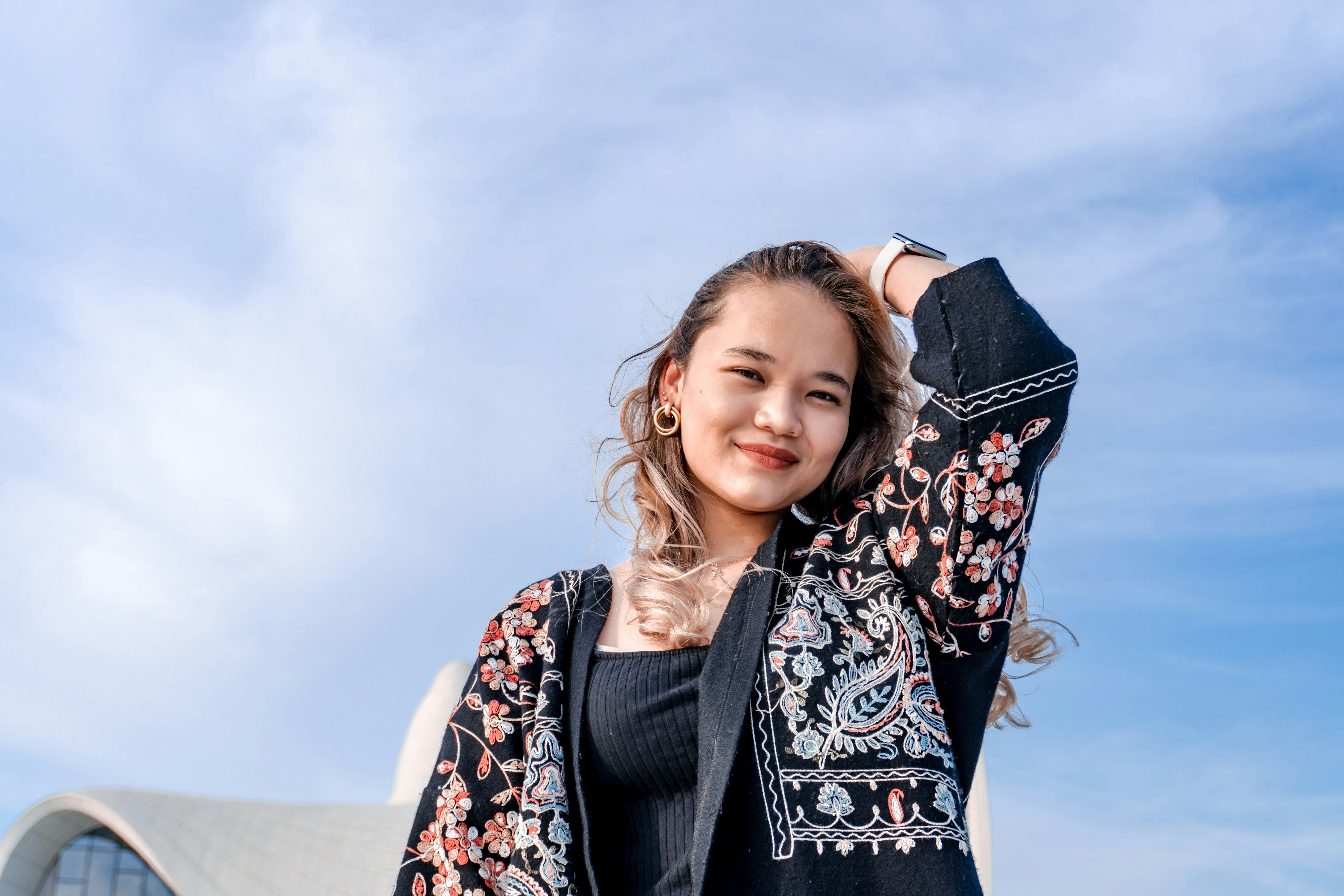 A young woman with her arm raised against blue sky