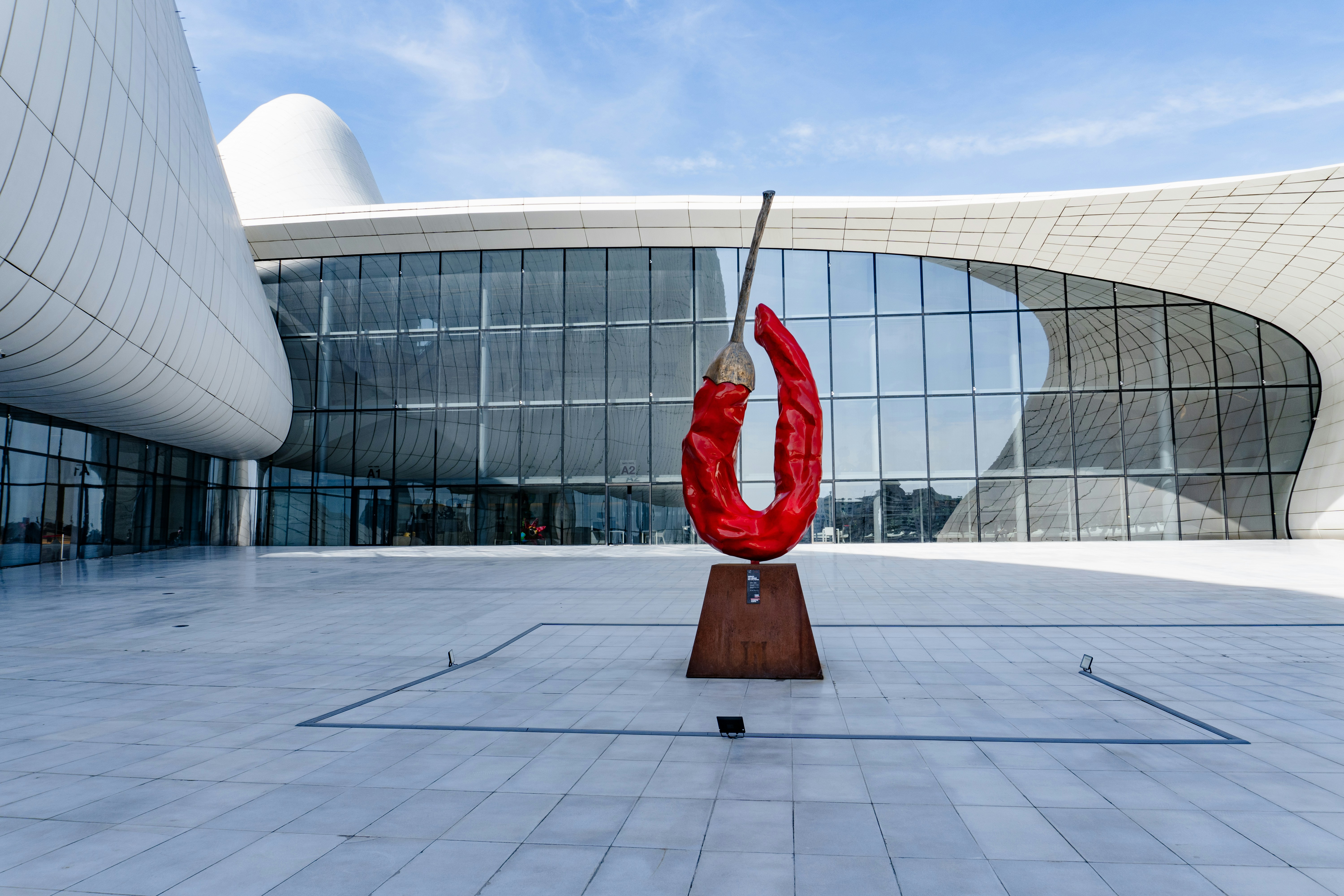 Red chili pepper sculpture in front of modern building