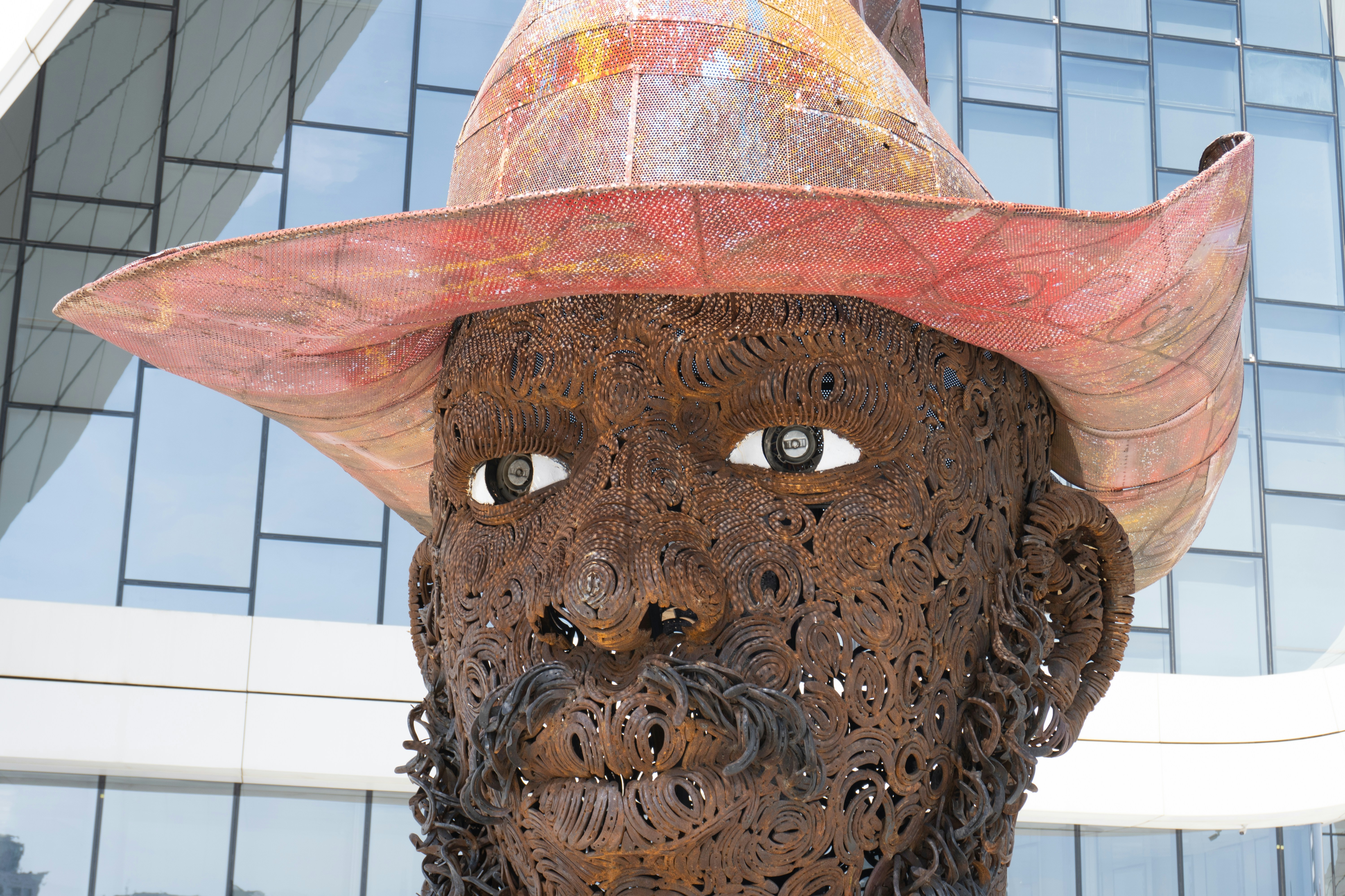 Large metal sculpture of a man's head wearing a hat.