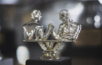 Silver trophy depicts two men arm wrestling