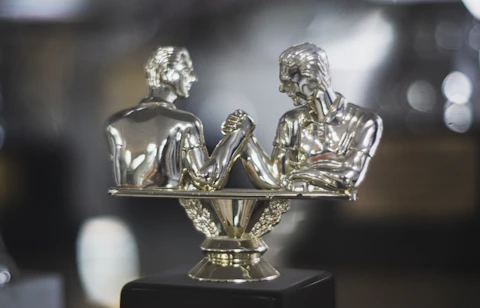 Silver trophy depicts two men arm wrestling