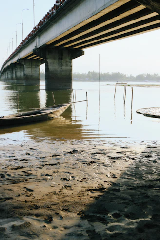 A long bridge over a calm river with a boat.