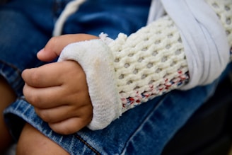 Child's arm in a knitted cast and sling.