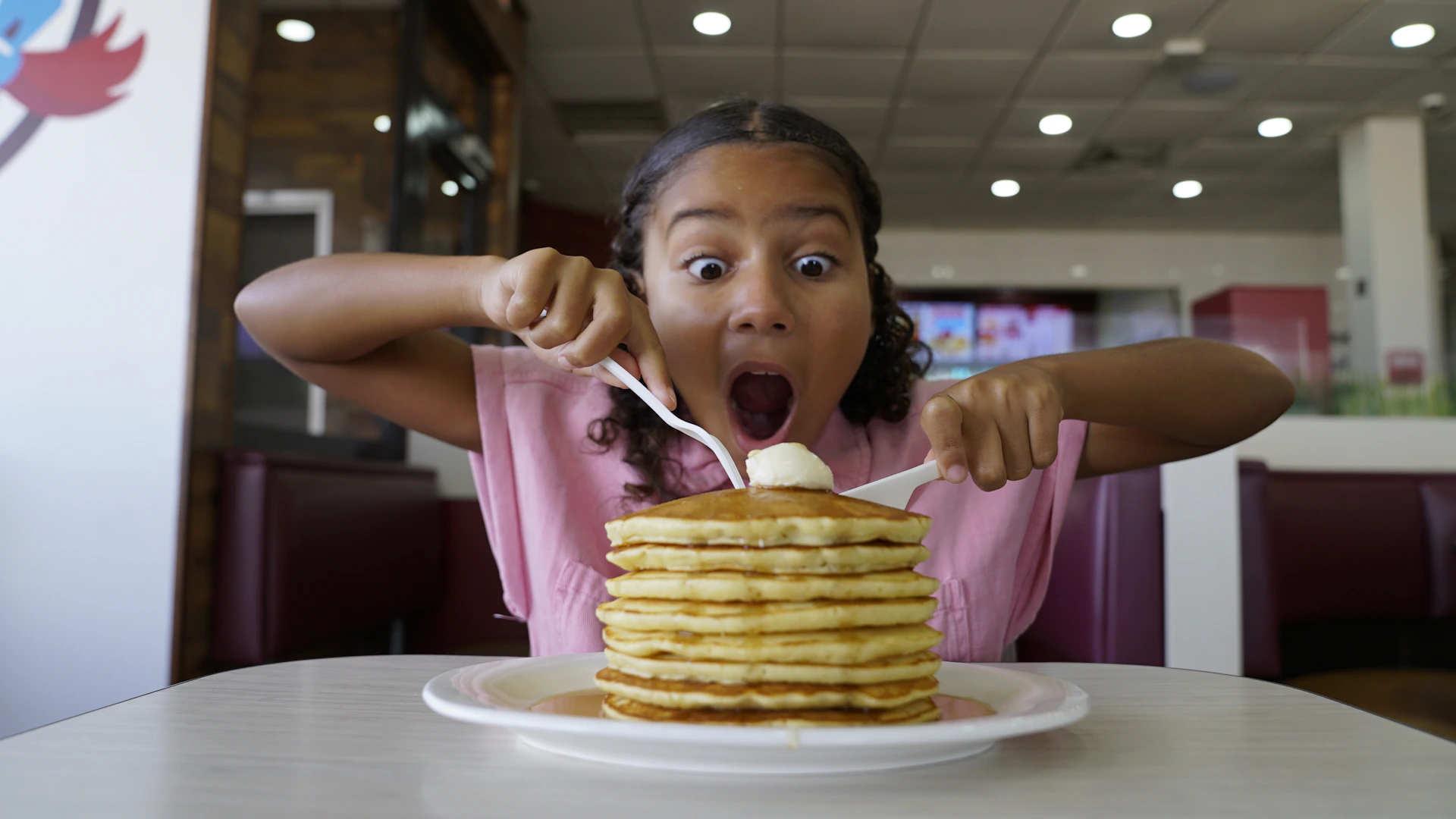 Girl with surprised expression eating stack of pancakes