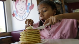 Young girl eating a large stack of pancakes