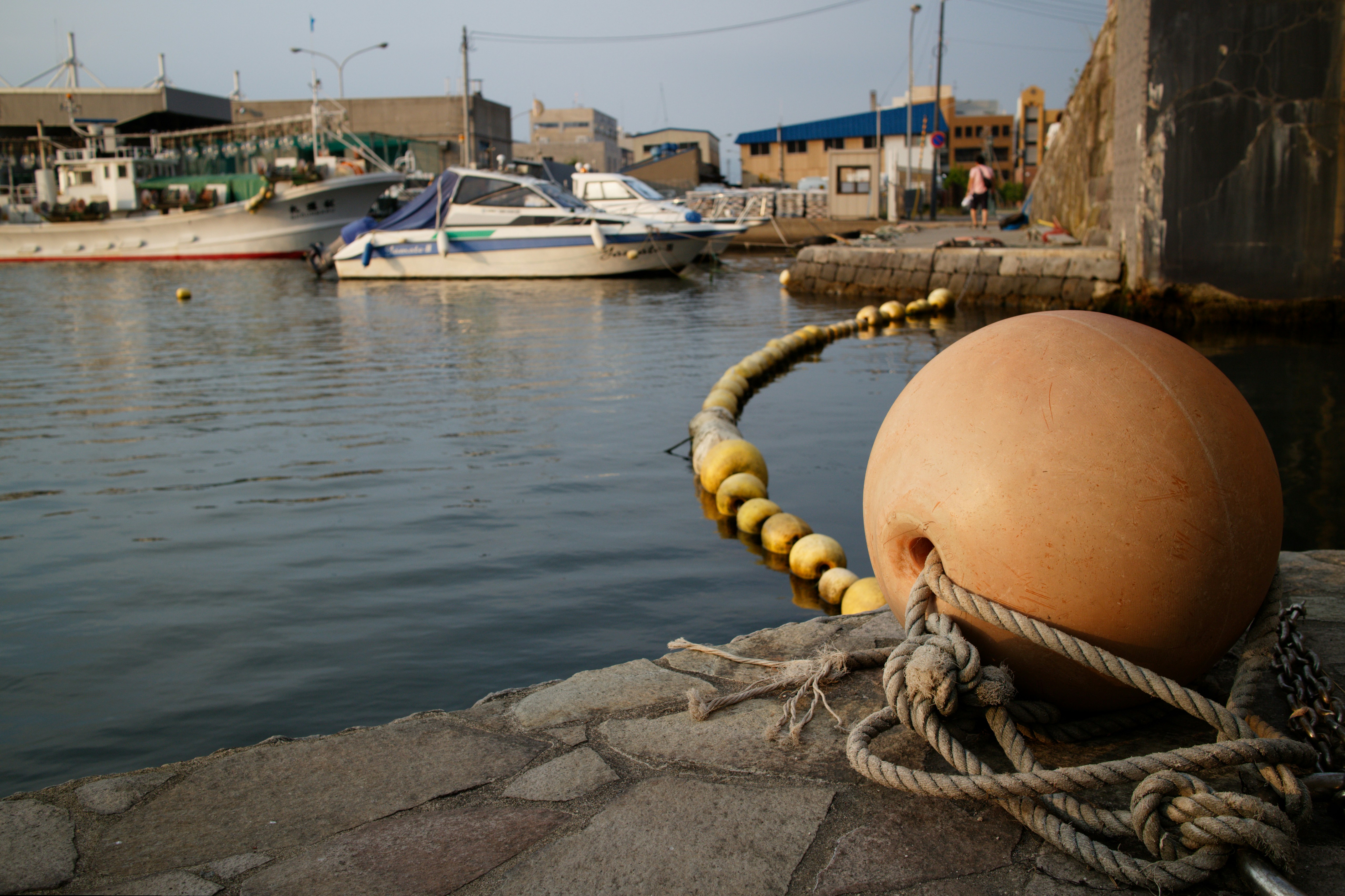 Boats docked in a harbor with a large buoy.