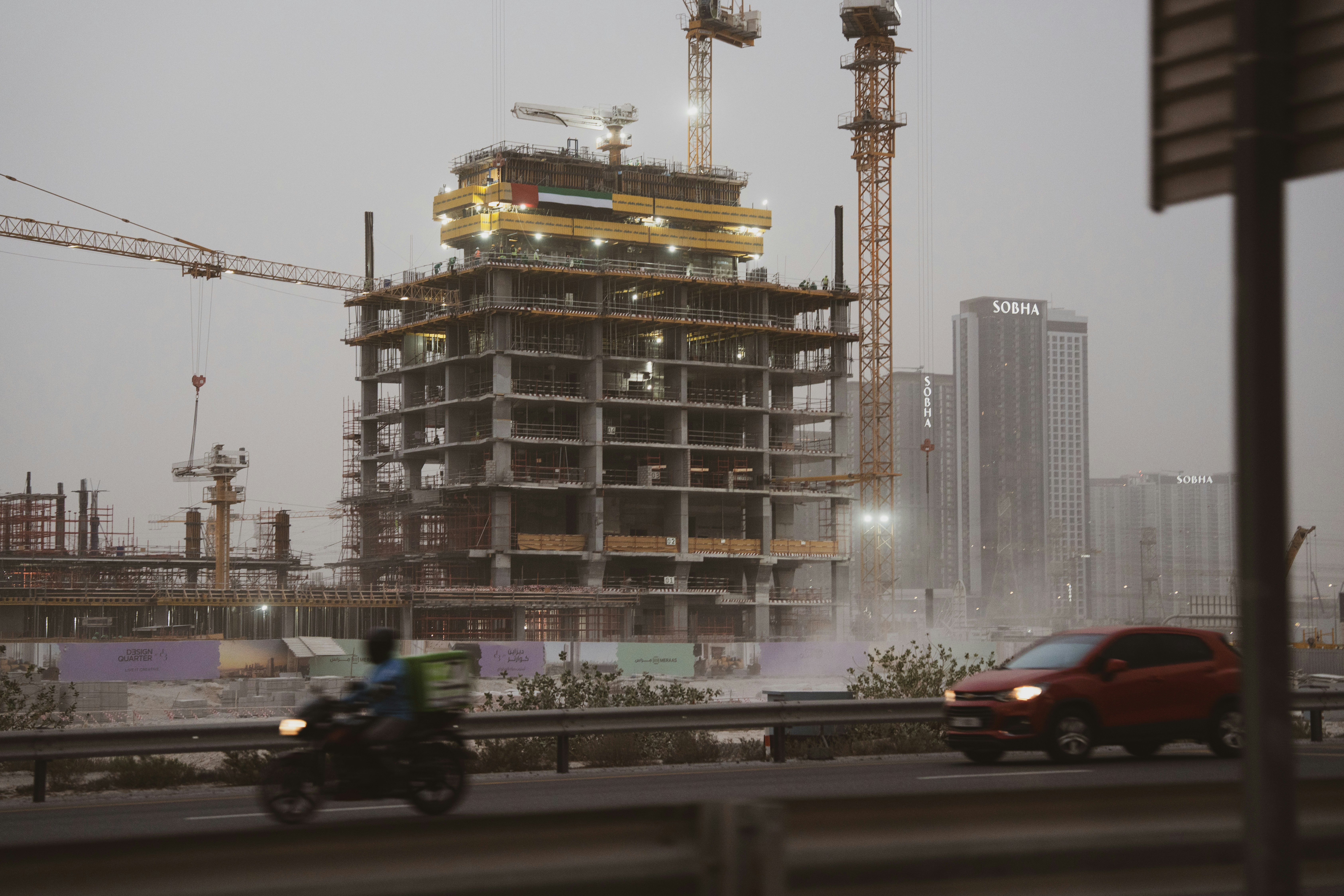 Construction site with cranes and unfinished building.