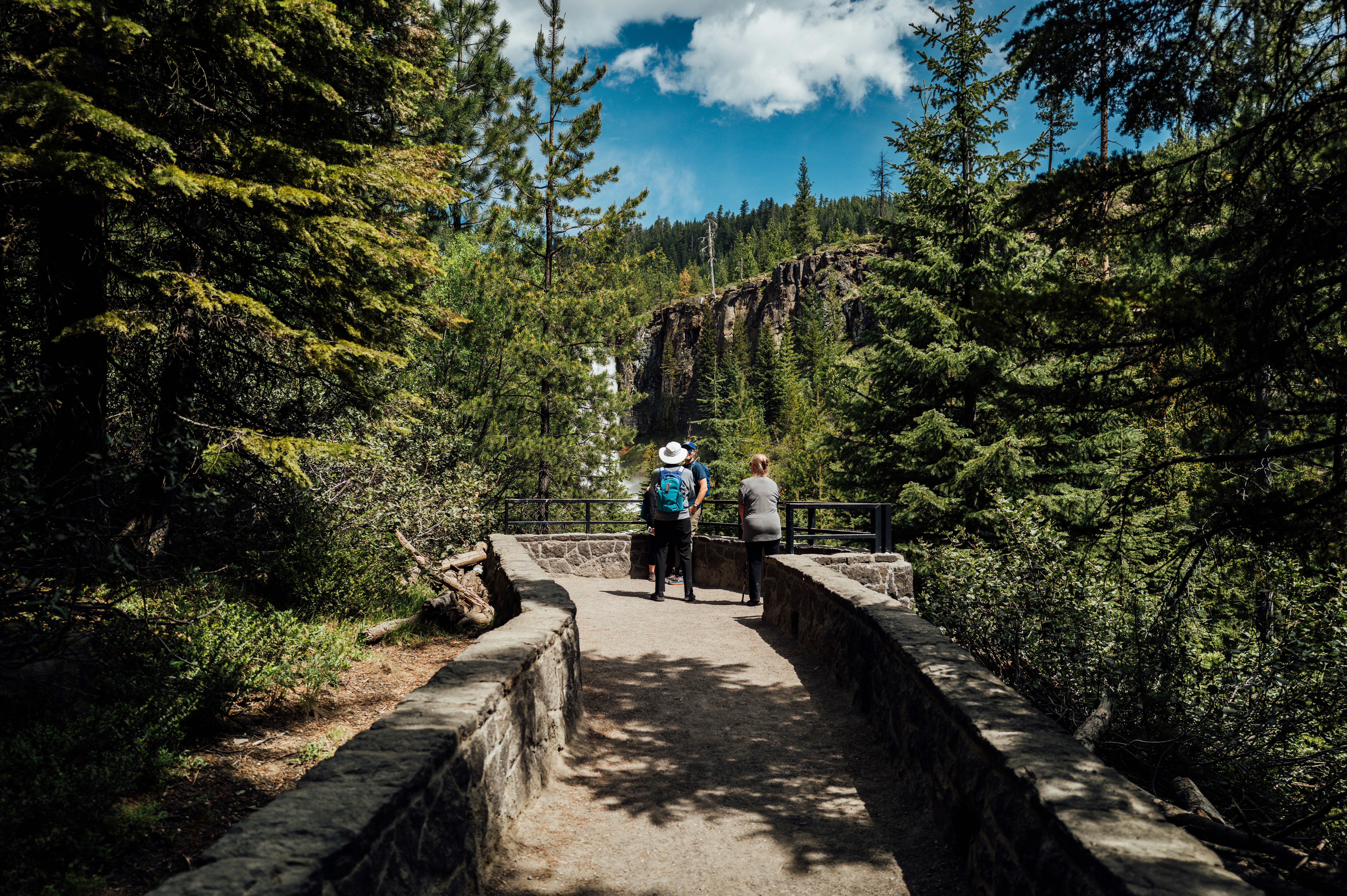 Two hikers on a stone path overlooking a waterfall.