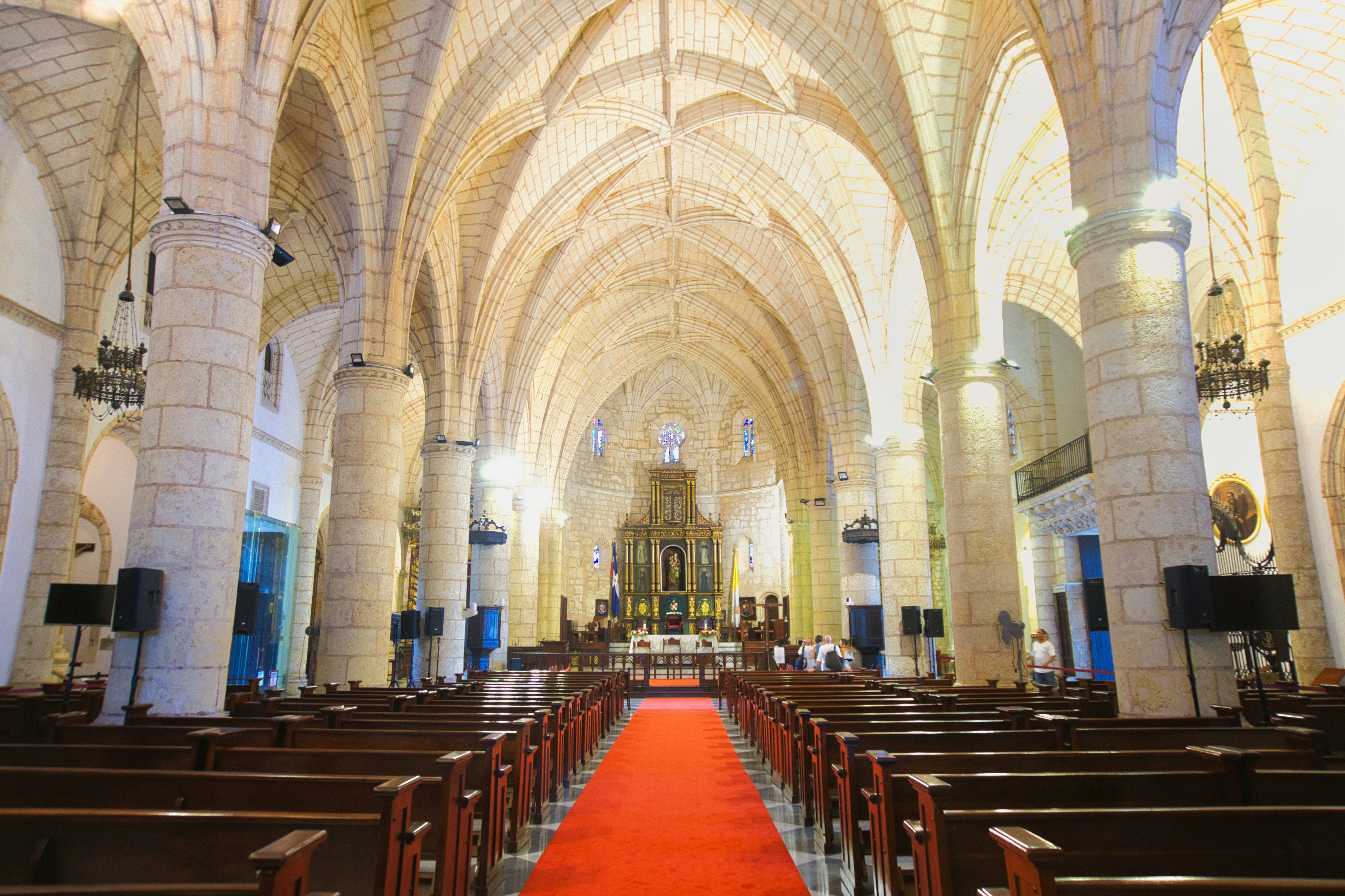 Interior de una gran catedral con pasillo de alfombra roja.