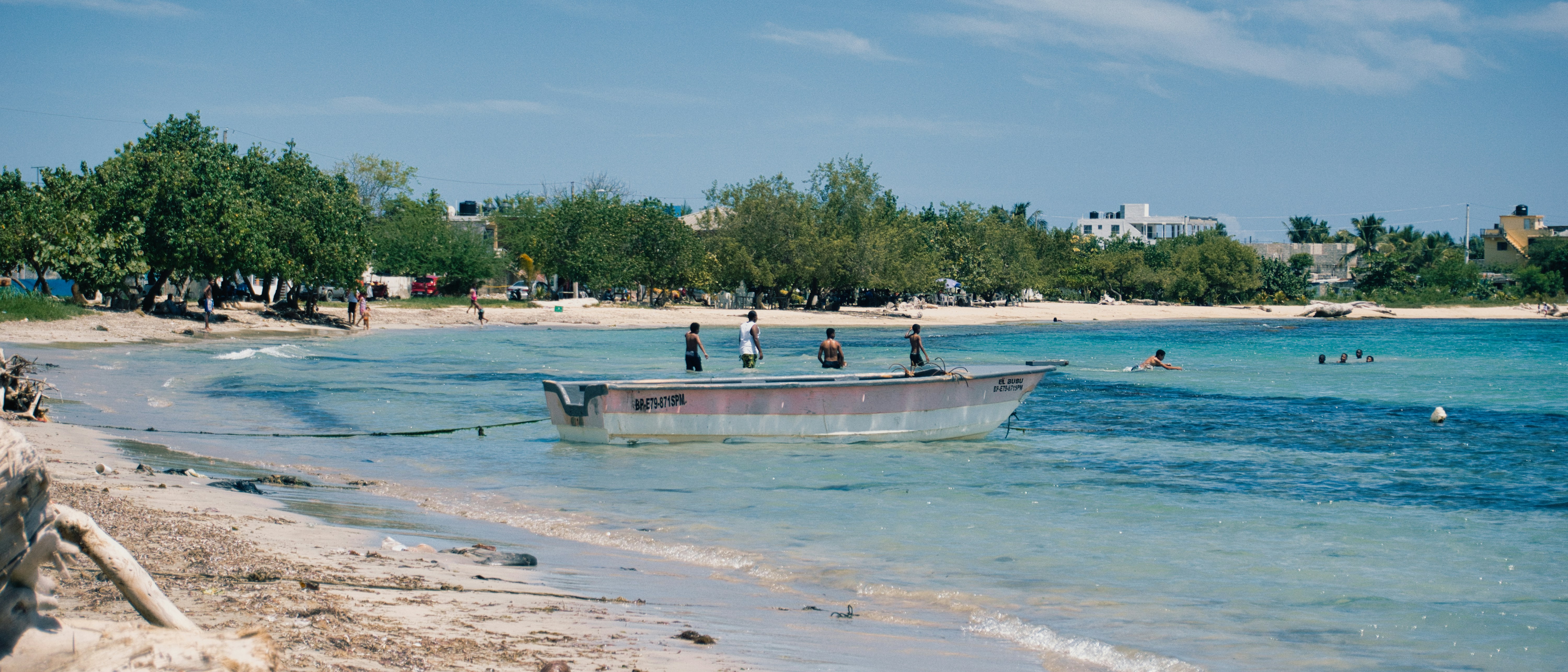 A long boat with people on board in turquoise water.