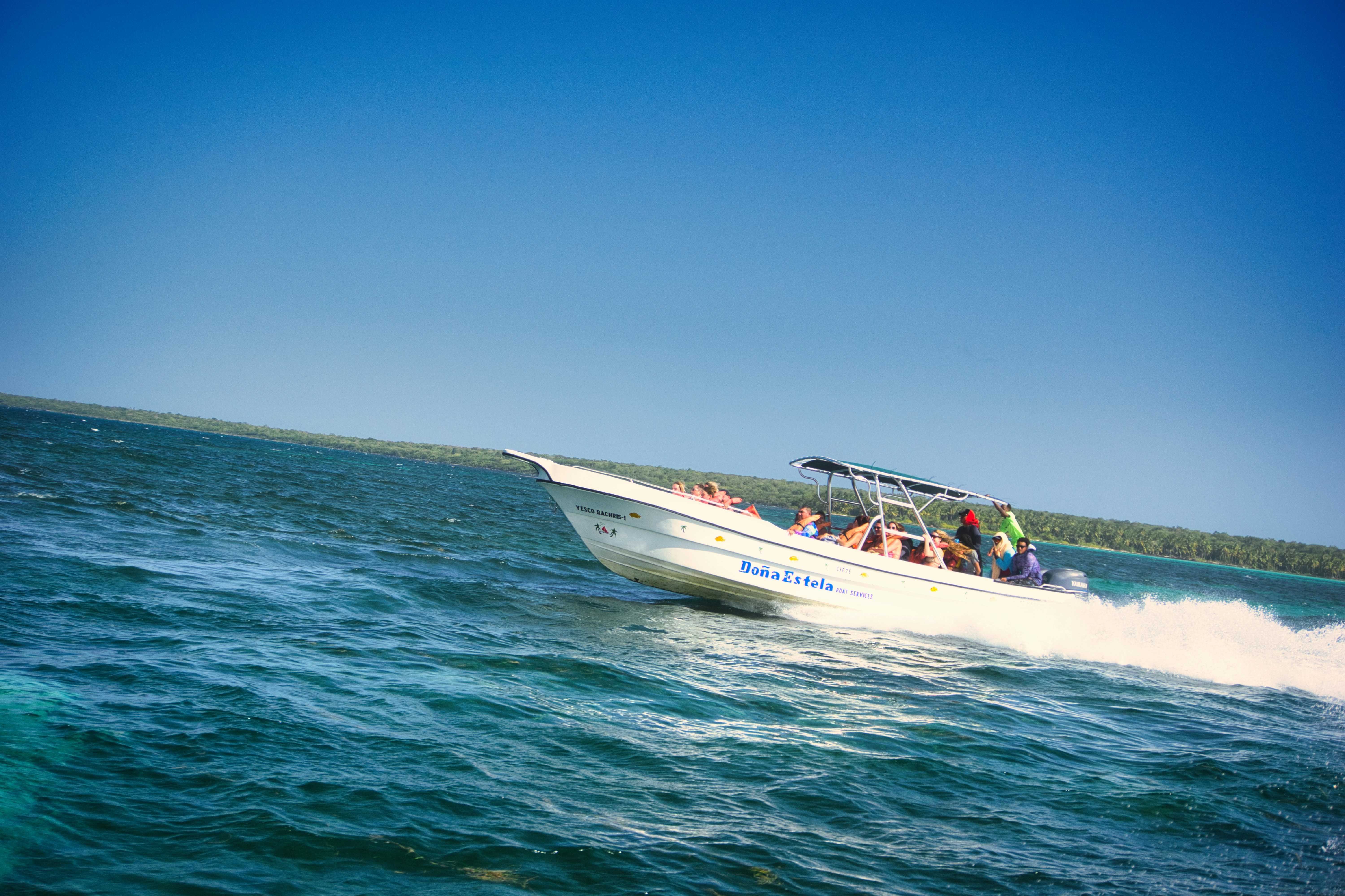Un bote blanco cruzando a toda velocidad el océano azul.
