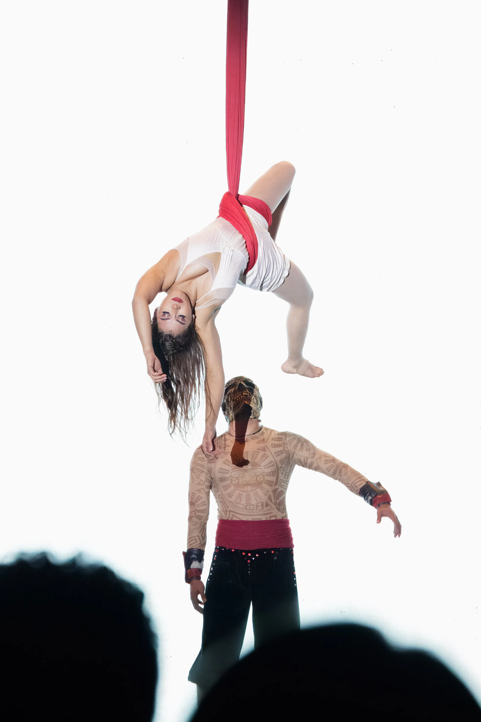 Dos artistas en telas aéreas rojas sobre fondo blanco
