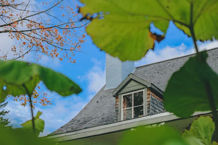 A grey shingle roof with a dormer window and a chimney