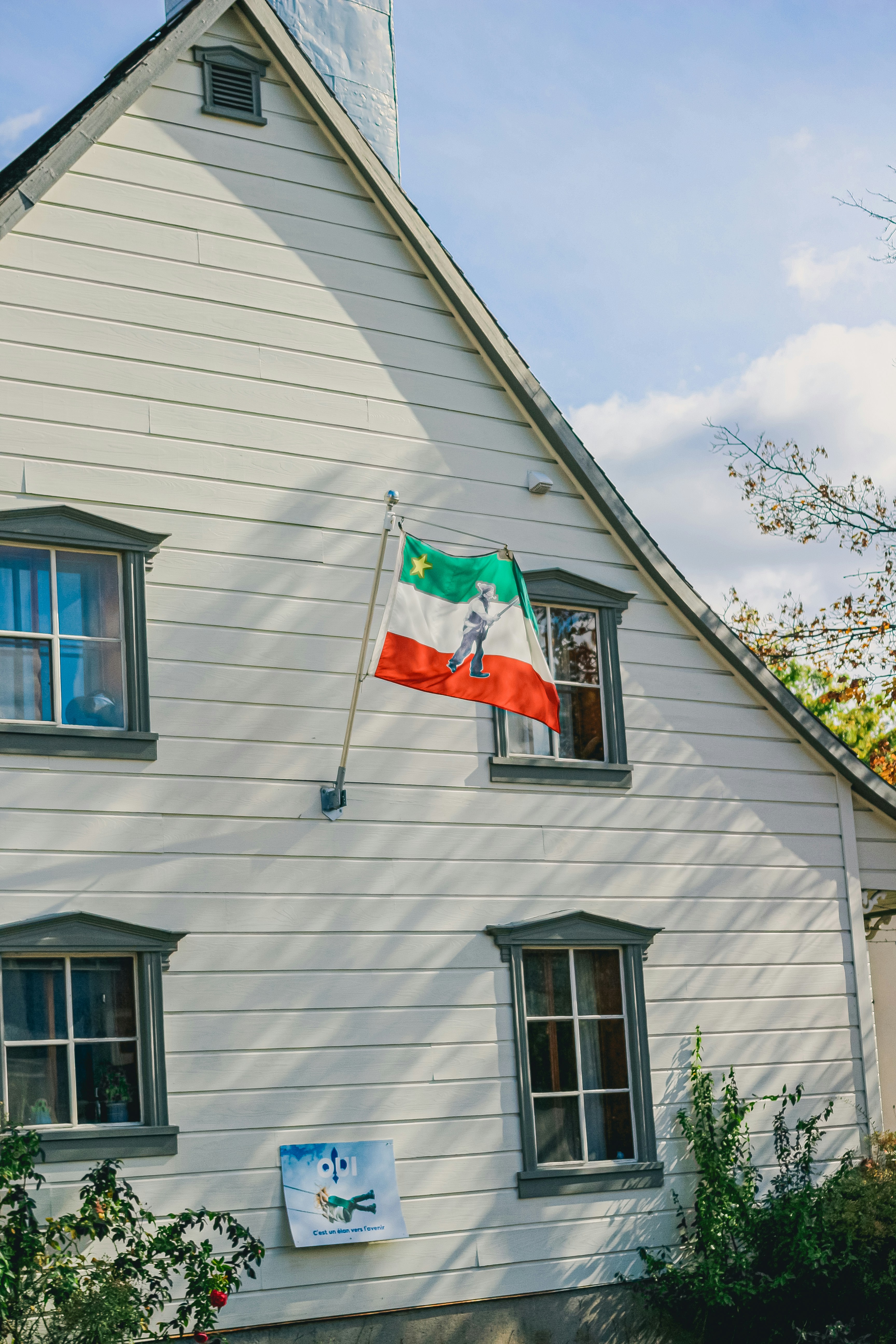 White house with a flag and two windows.