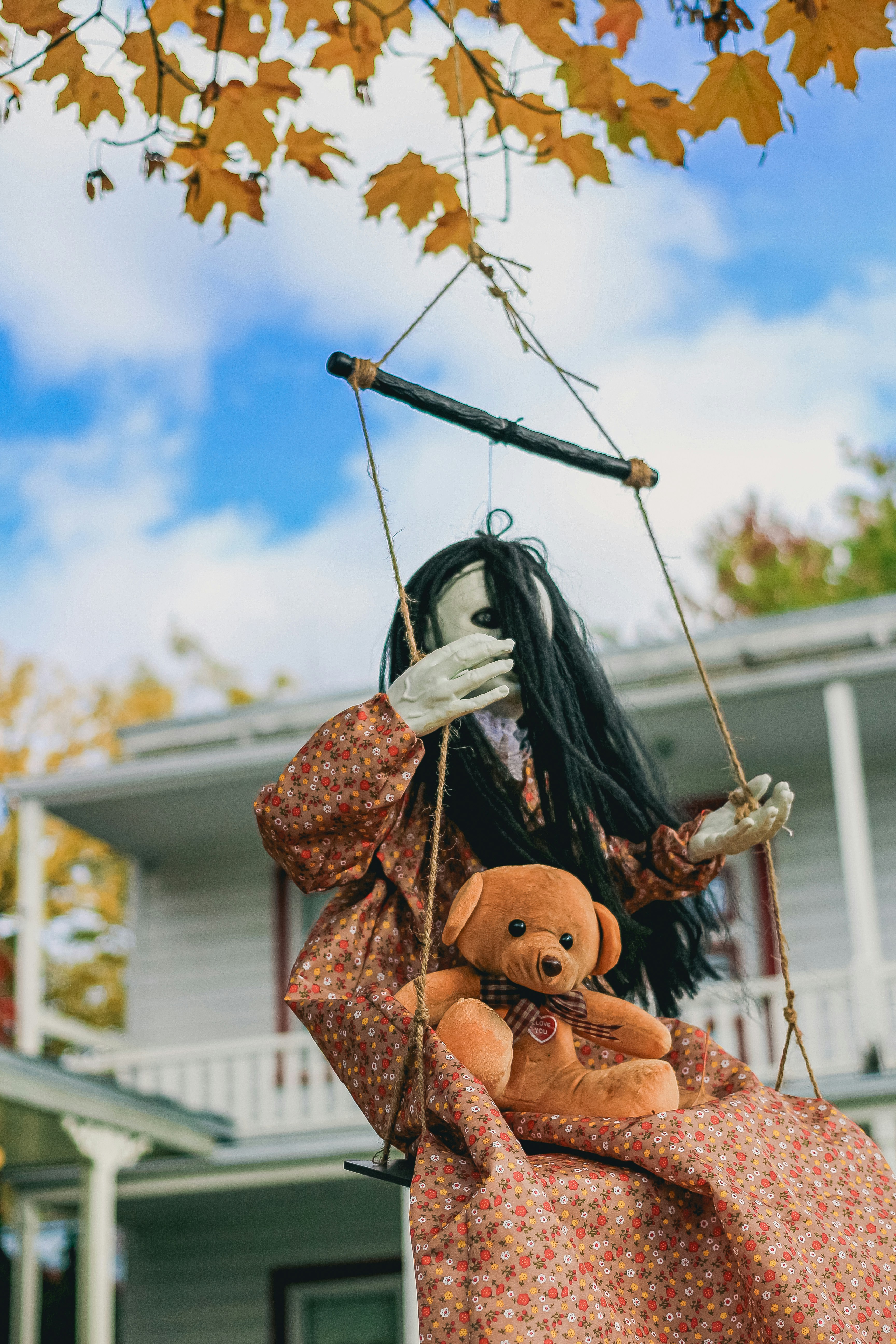 Creepy doll with teddy bear on a swing