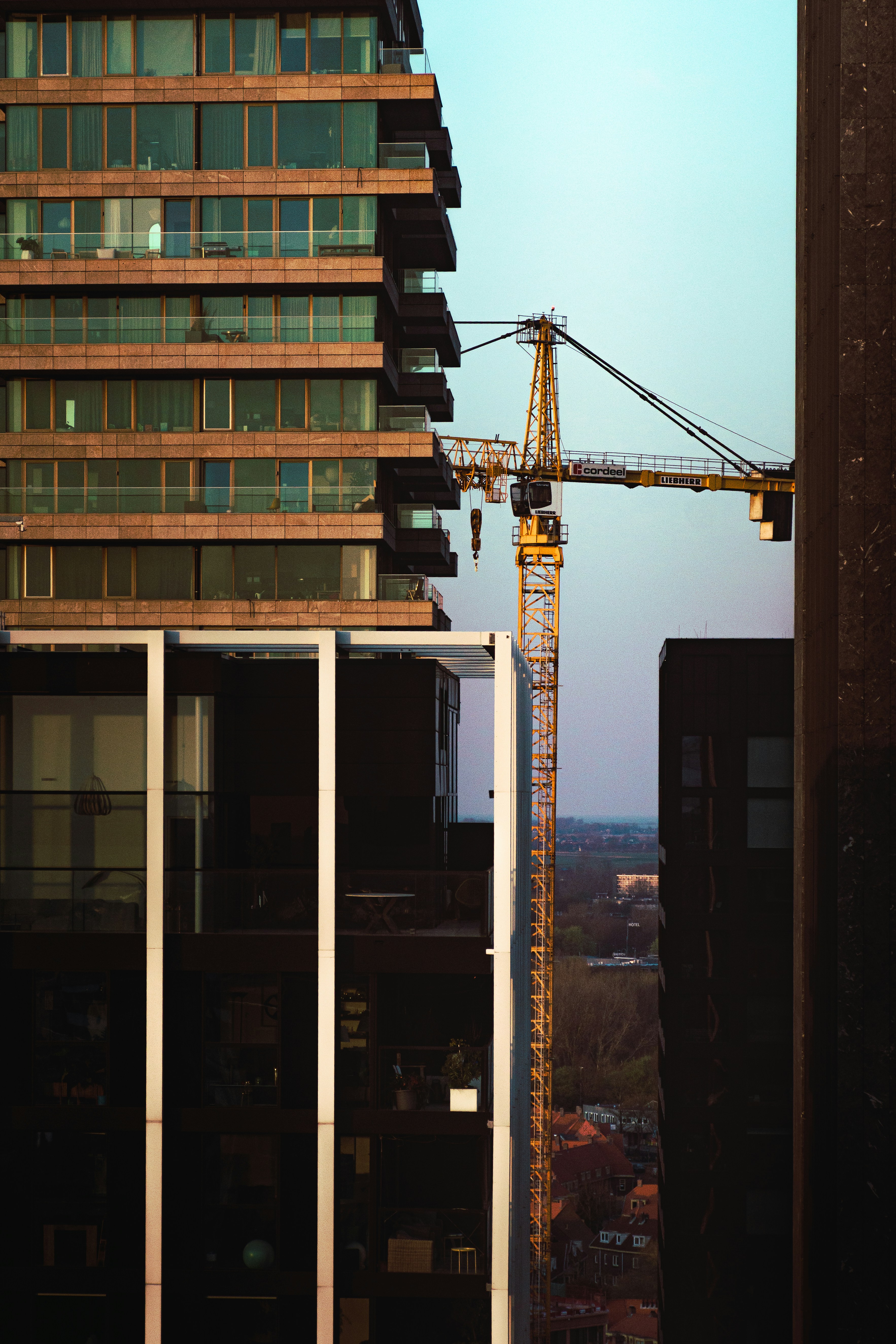 Construction crane between modern buildings at sunset