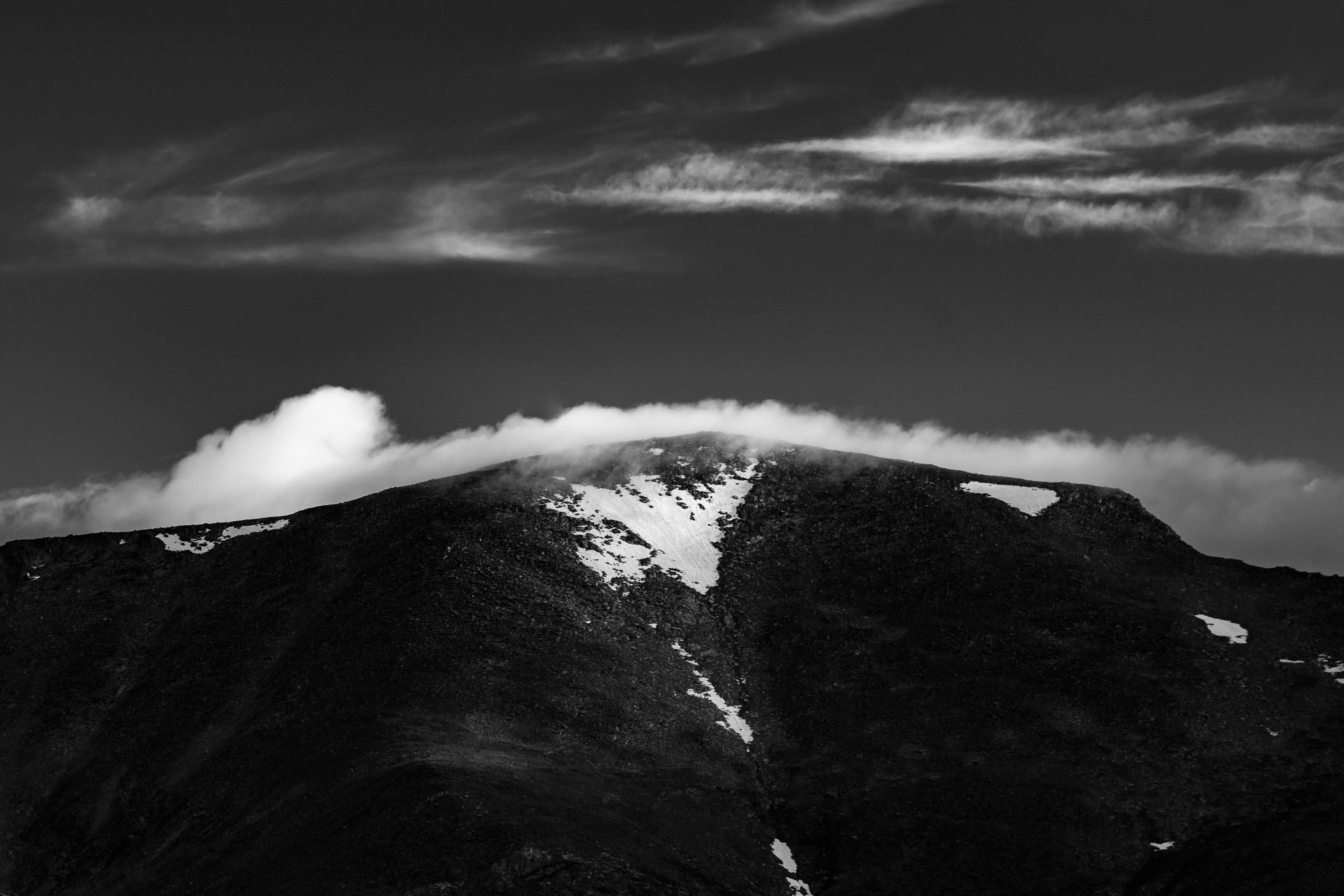 Bulutların üzerinde yükselen görkemli bir dağ zirvesi; bilgeliği, zorluğu ve doğanın derin anlamını simgeleyen manzara.