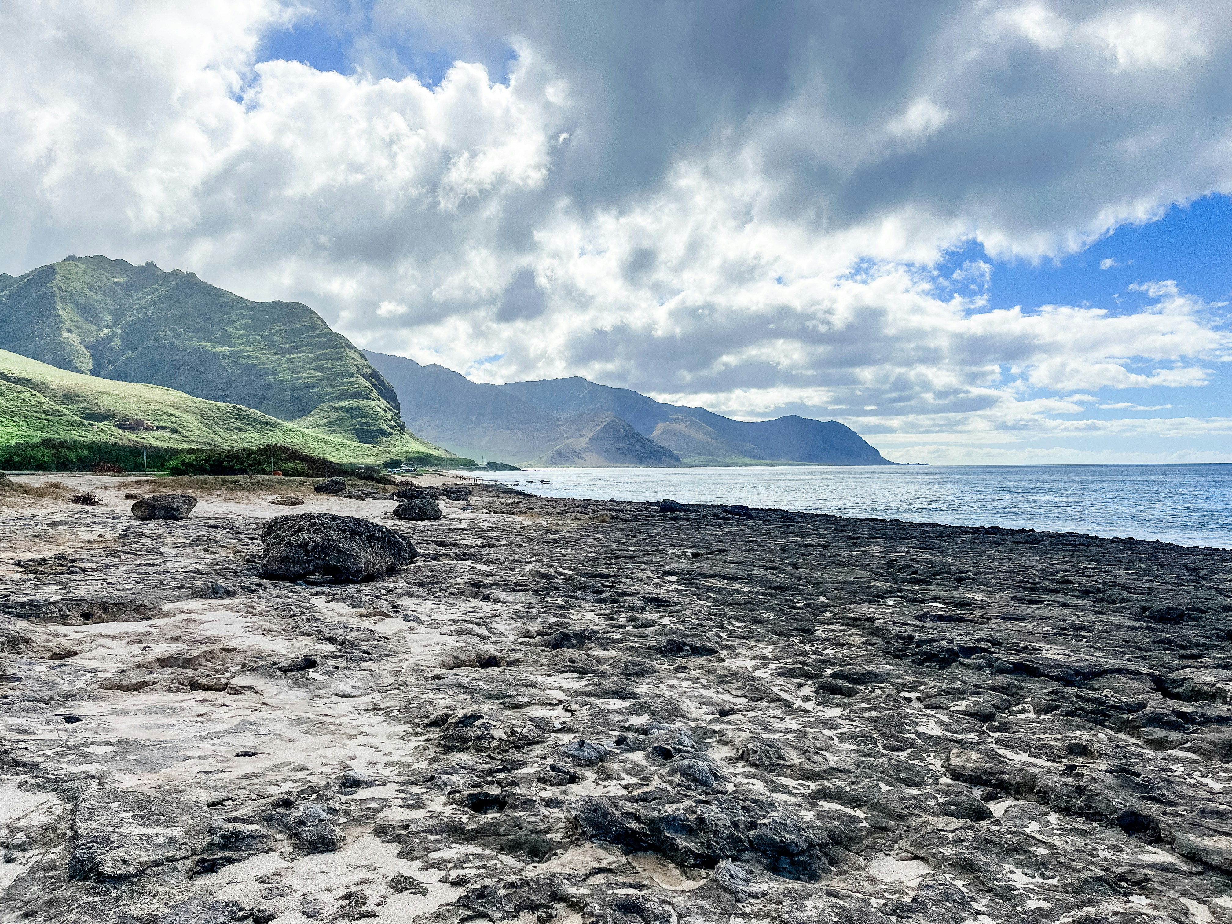 Rocky North Shore Oahu coastline backed by green mountains under a soft sky
