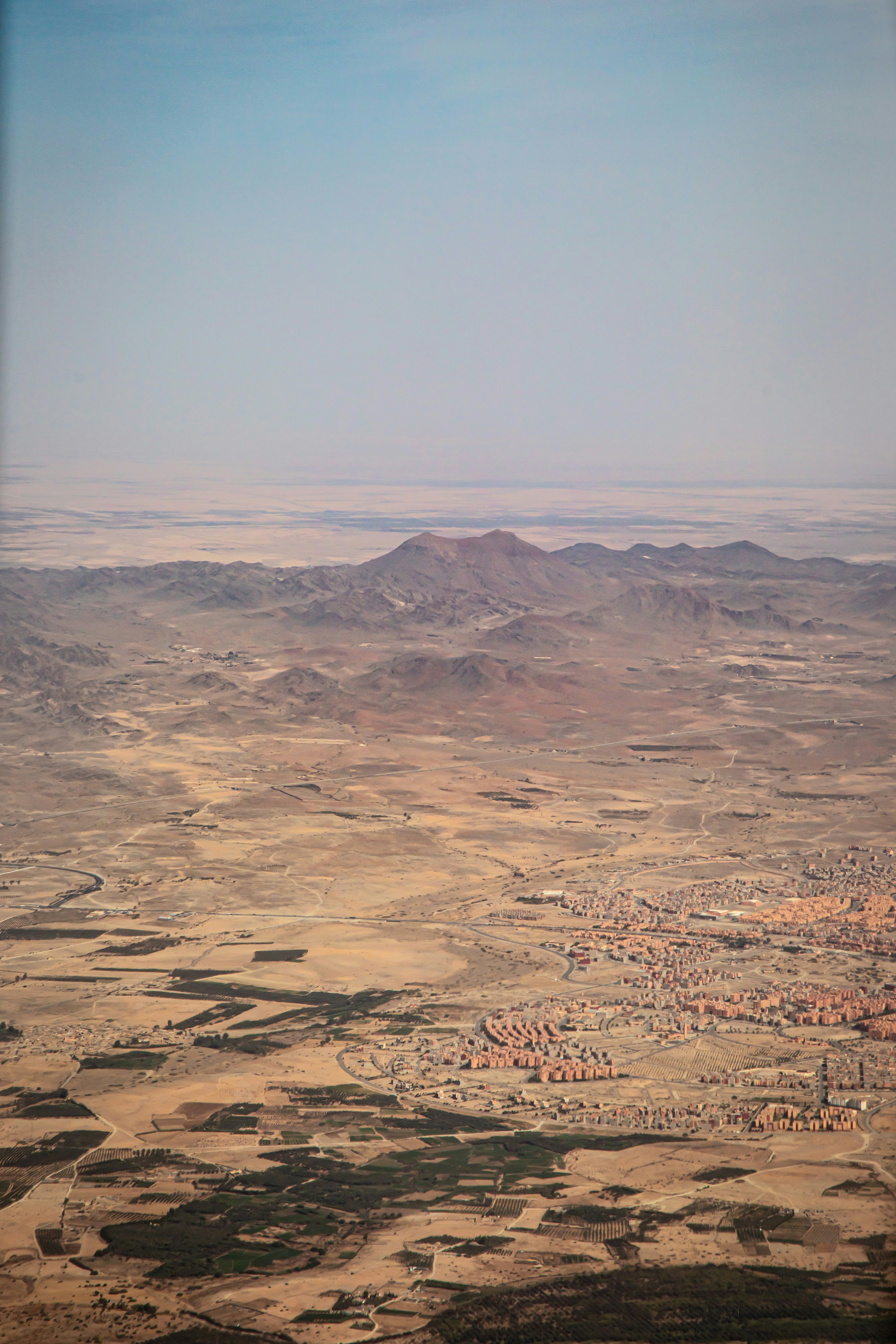 Arid landscape with mountains and scattered buildings.