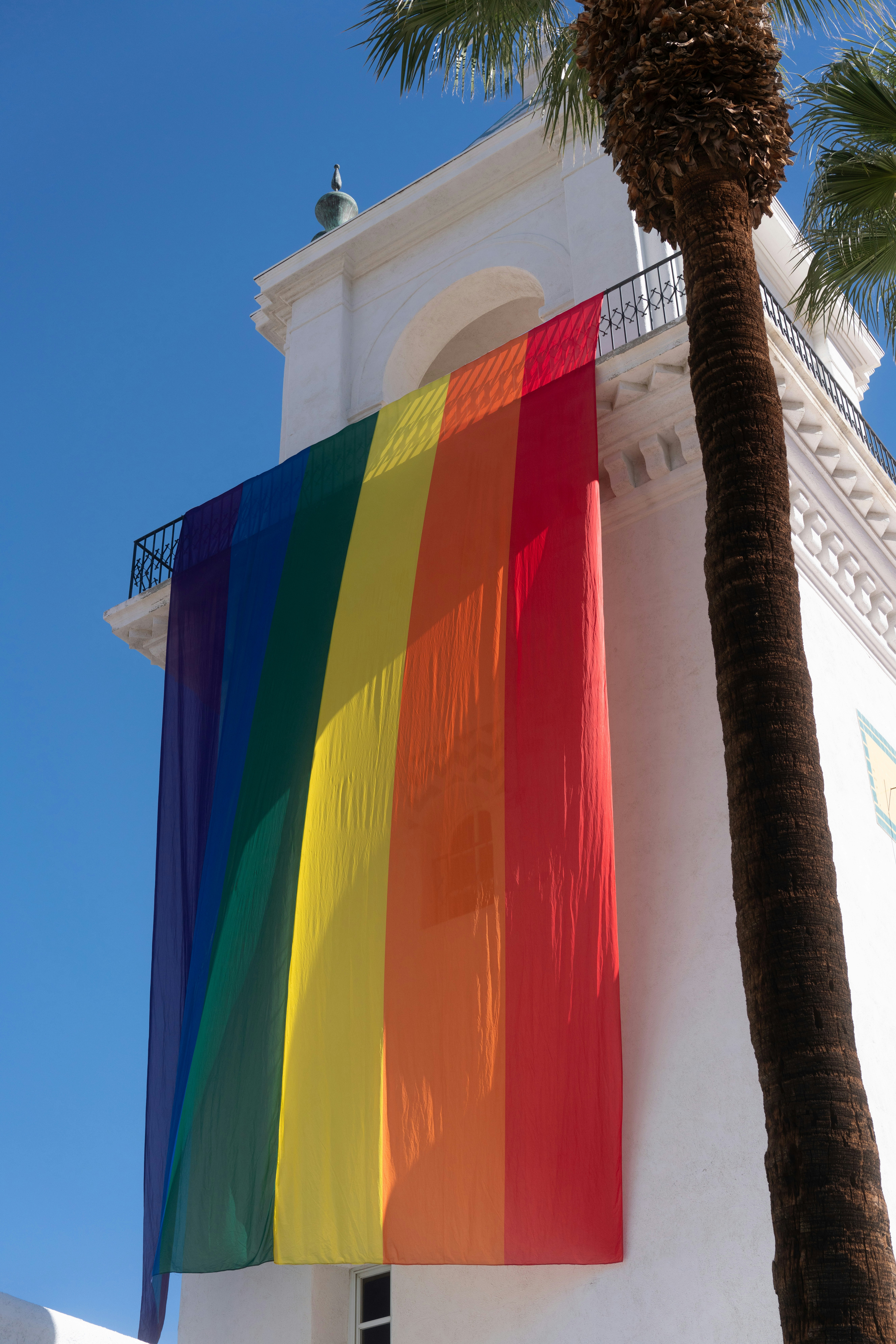 Eine Regenbogenflagge hängt an einem weißen Gebäude.