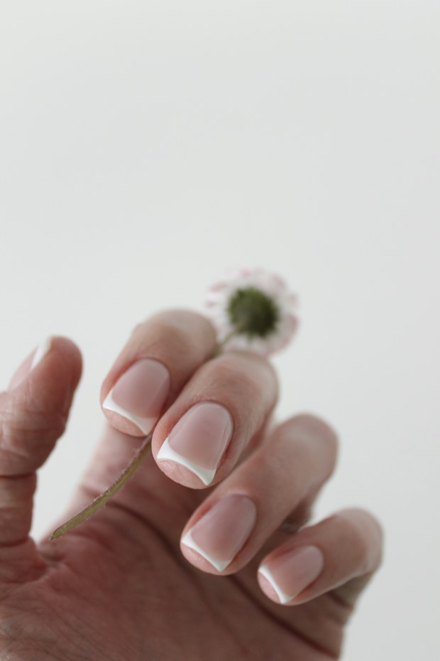 French manicure holding a small flower