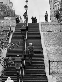 Man walks up grand staircase with people above