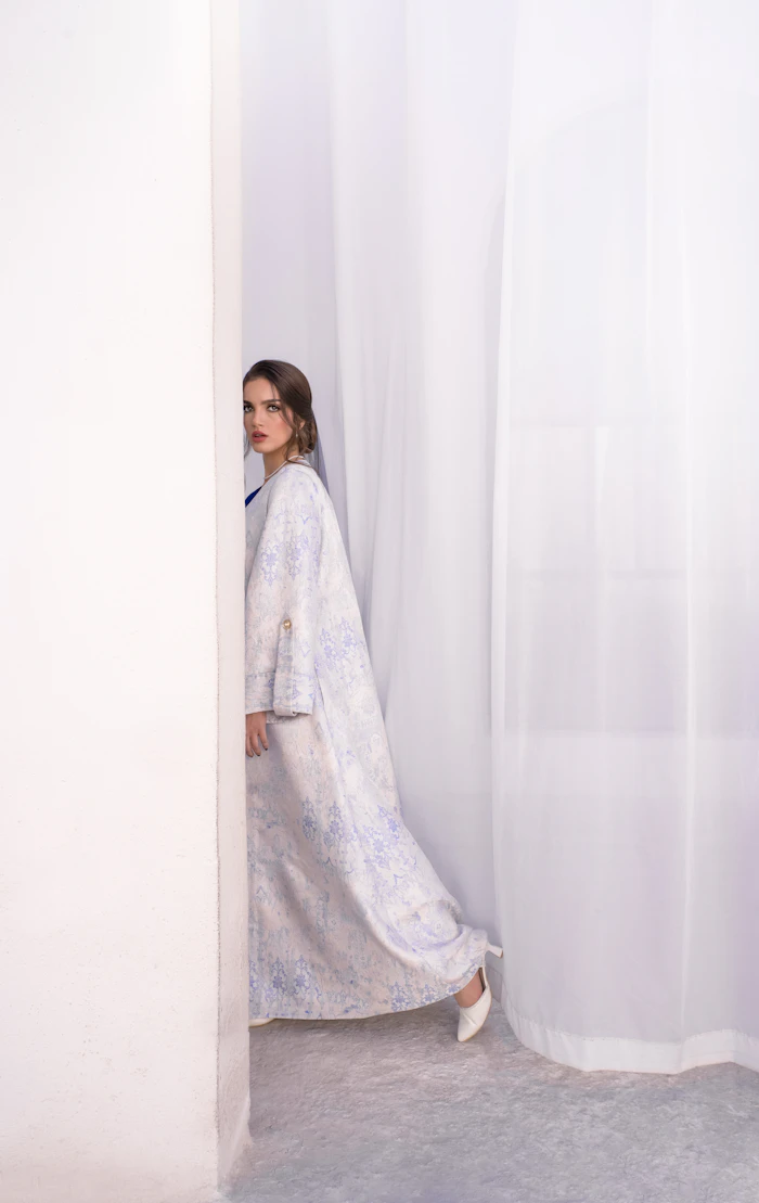 Linen Open Abaya in pale floral, shown by a draped curtain.