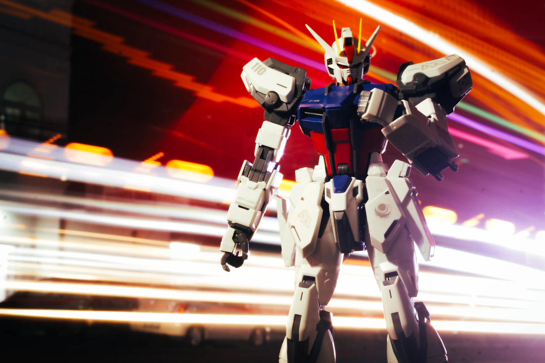 A white, blue and red robot model striding in front of streaks of colored light