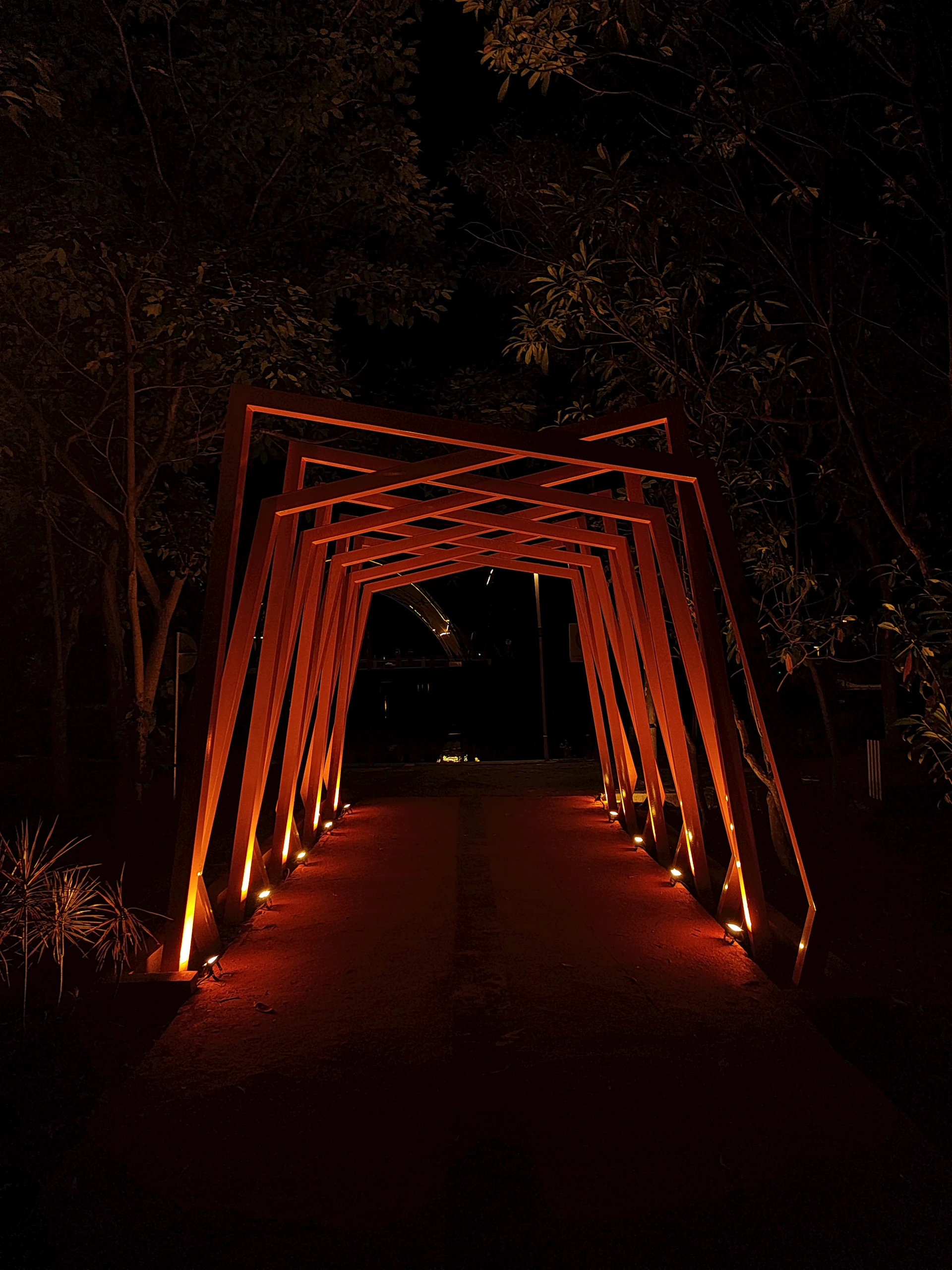 Illuminated wooden archway leading into darkness at night