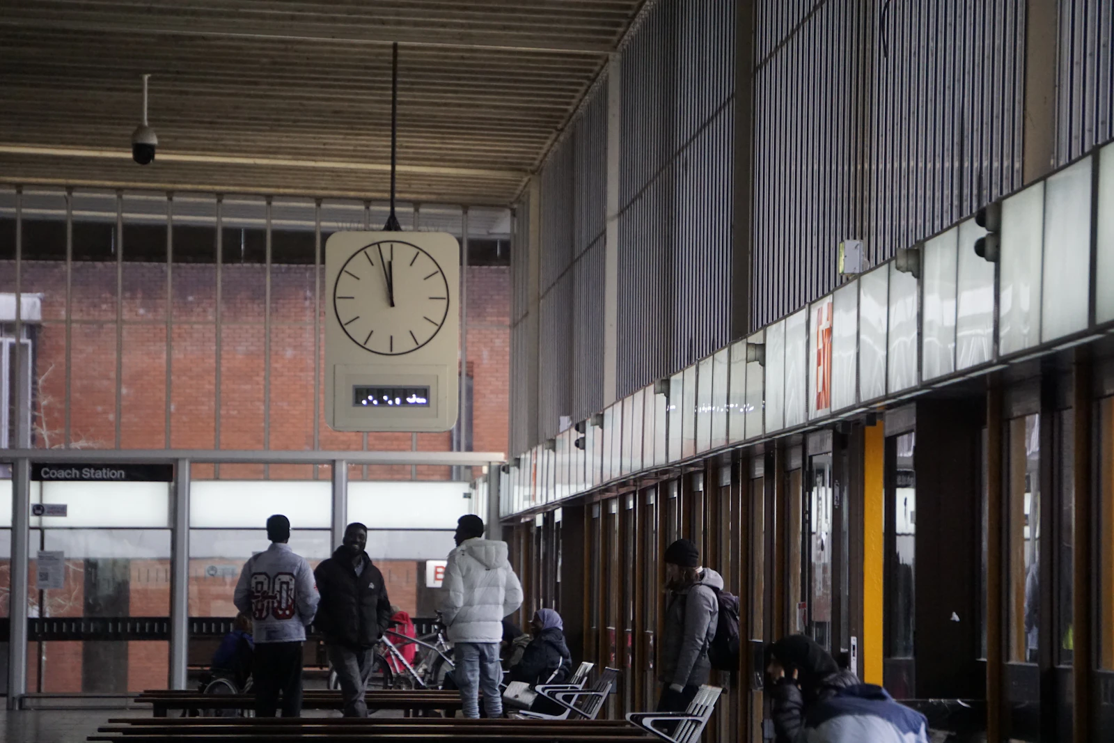 People waiting beneath a large station clock