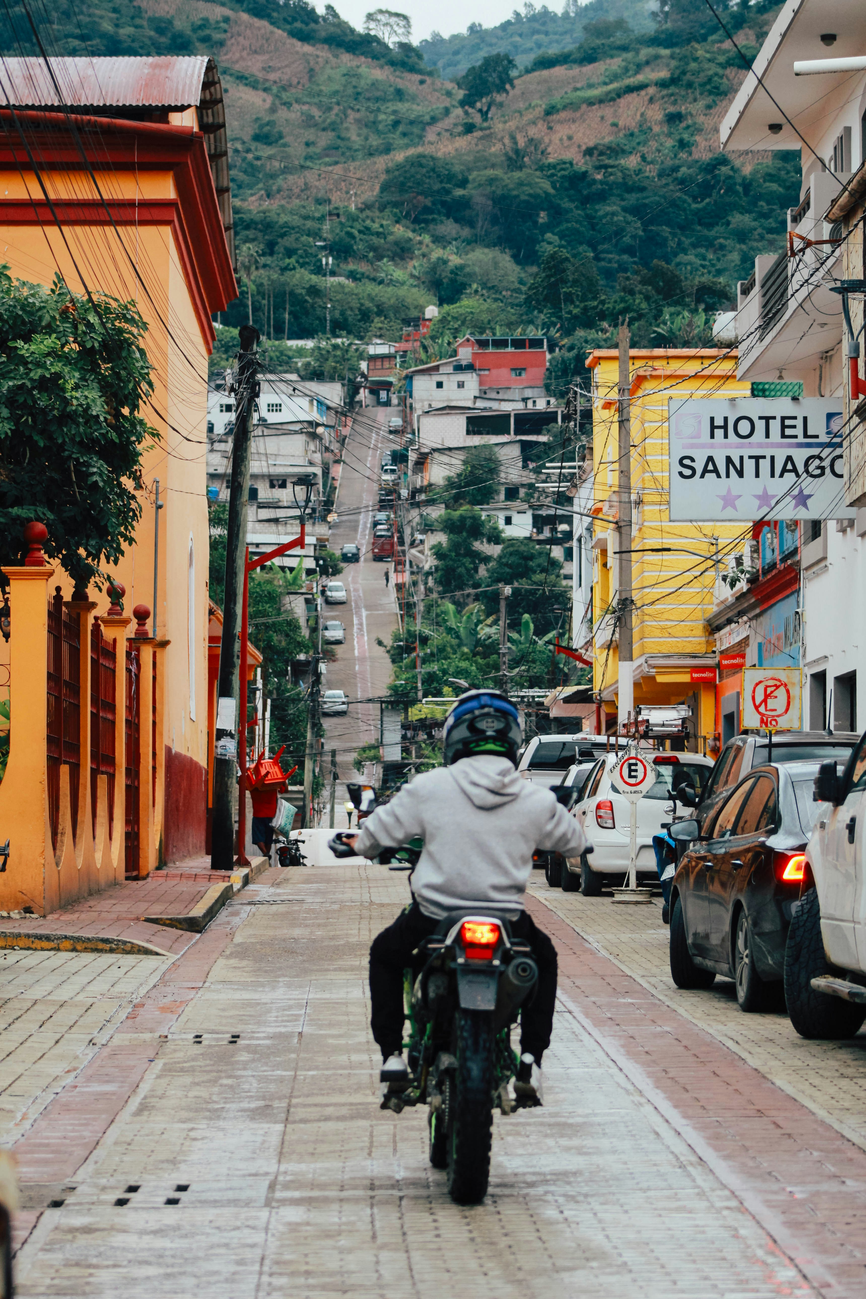 <li>8 Off-the-Beaten-Path Destinations in South America You’ll Love</li> – Man rides motorcycle up a steep, colorful street.