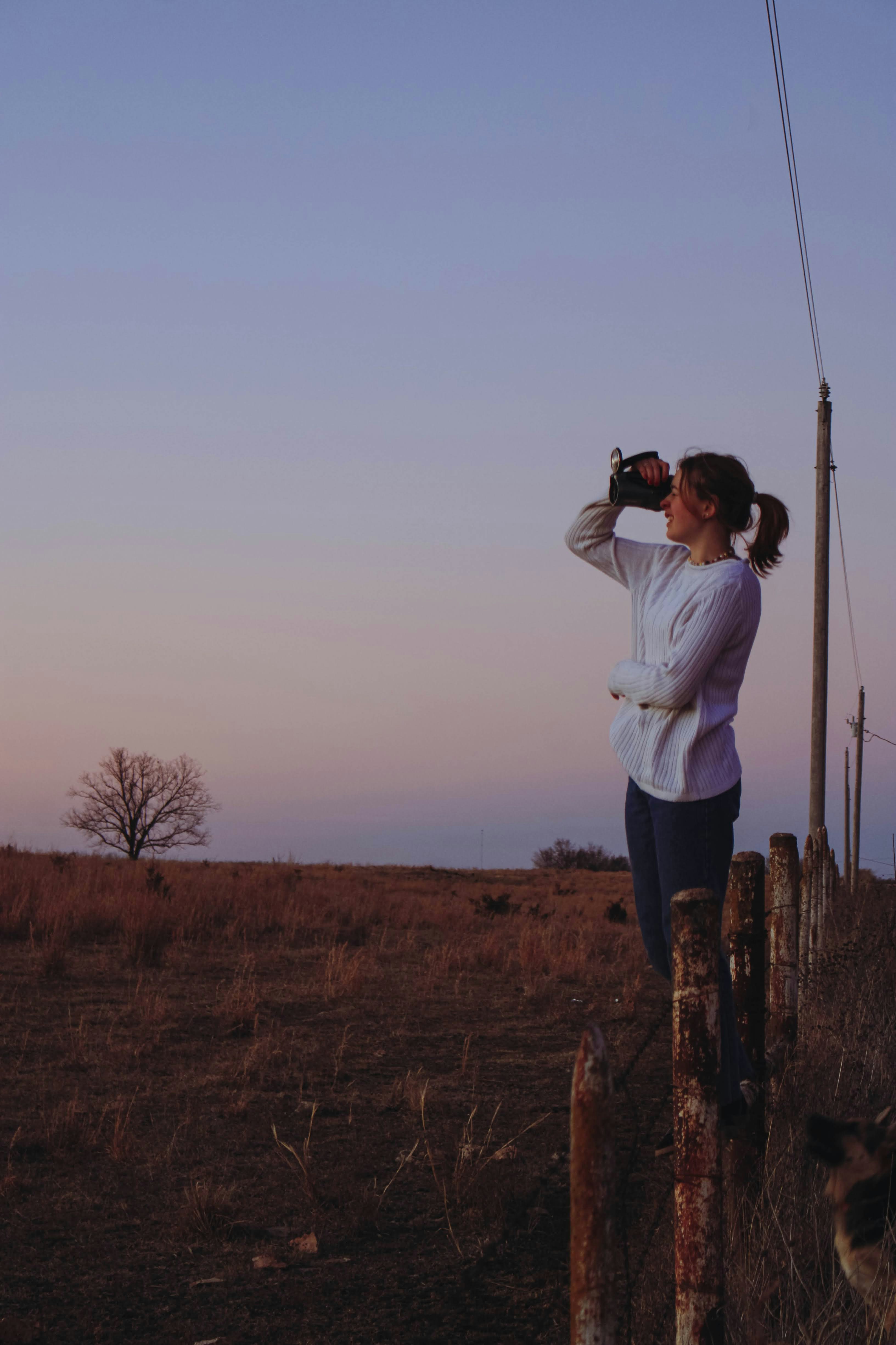 Woman looking through binoculars at sunset
