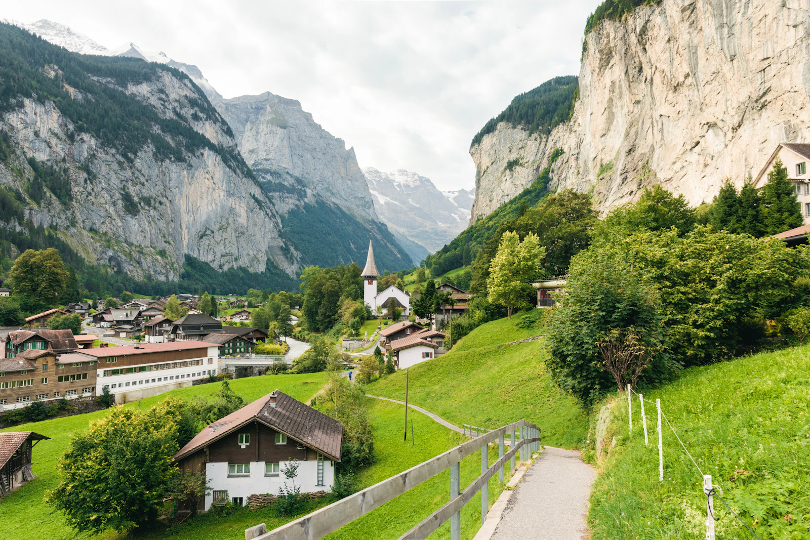 Village alpin dans une vallée verdoyante, clocher au centre (image d'illustration)