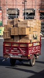 Red trailer loaded with cardboard boxes on street.