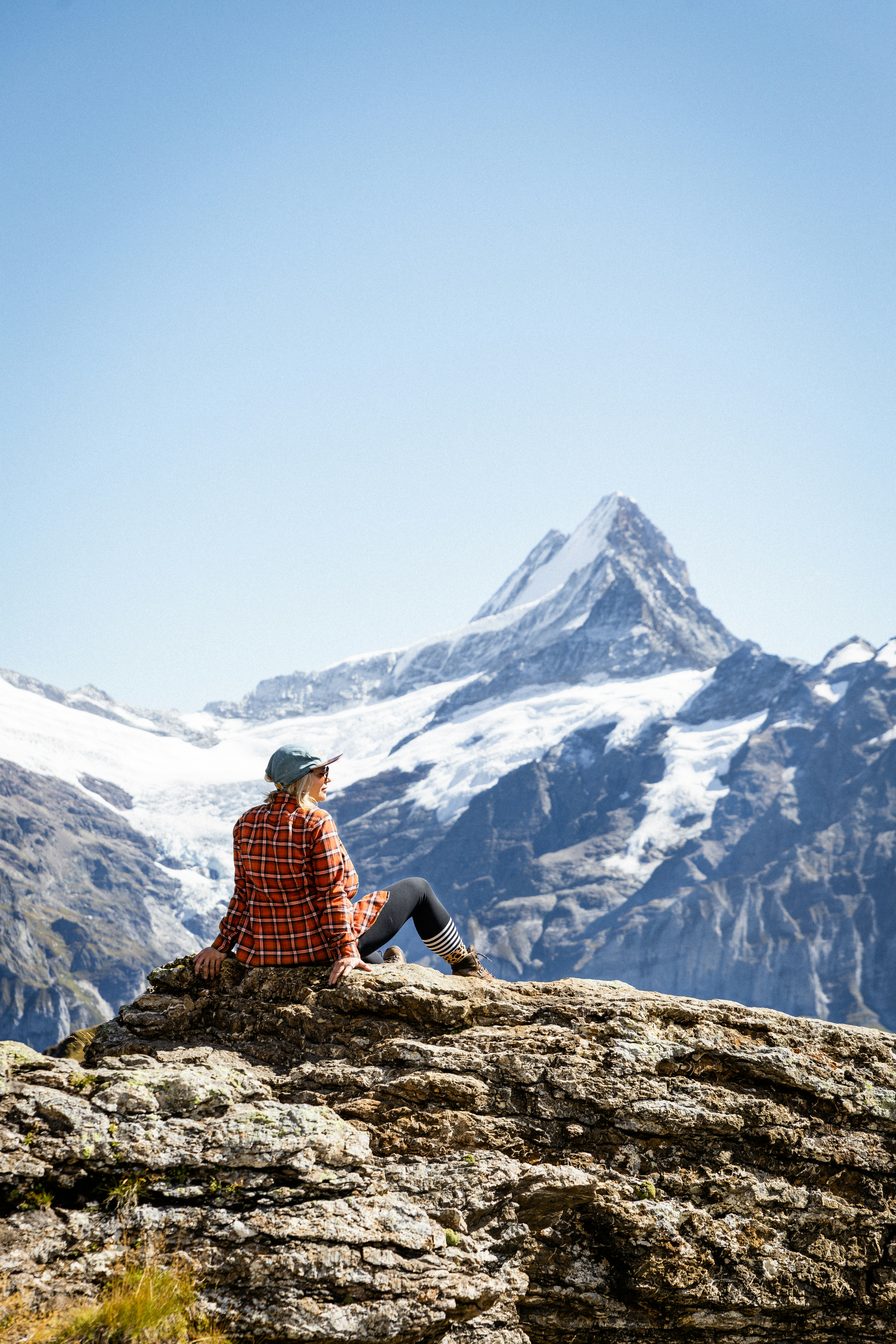 Woman sitting on rock overlooking snowy mountain peak