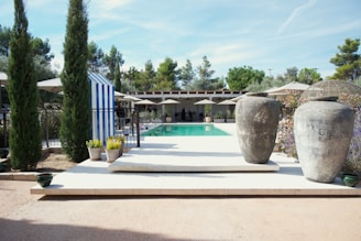 Two large urns flank a swimming pool area