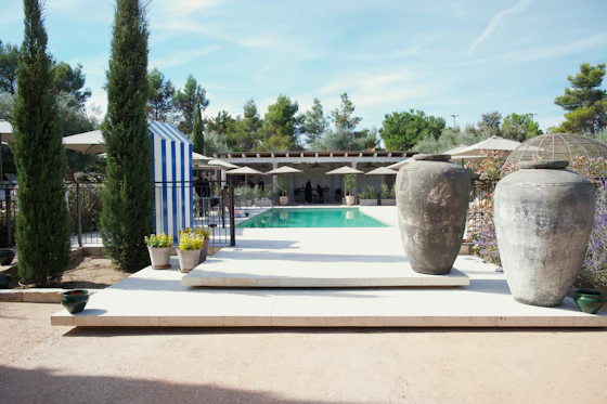 Two large urns flank a swimming pool area