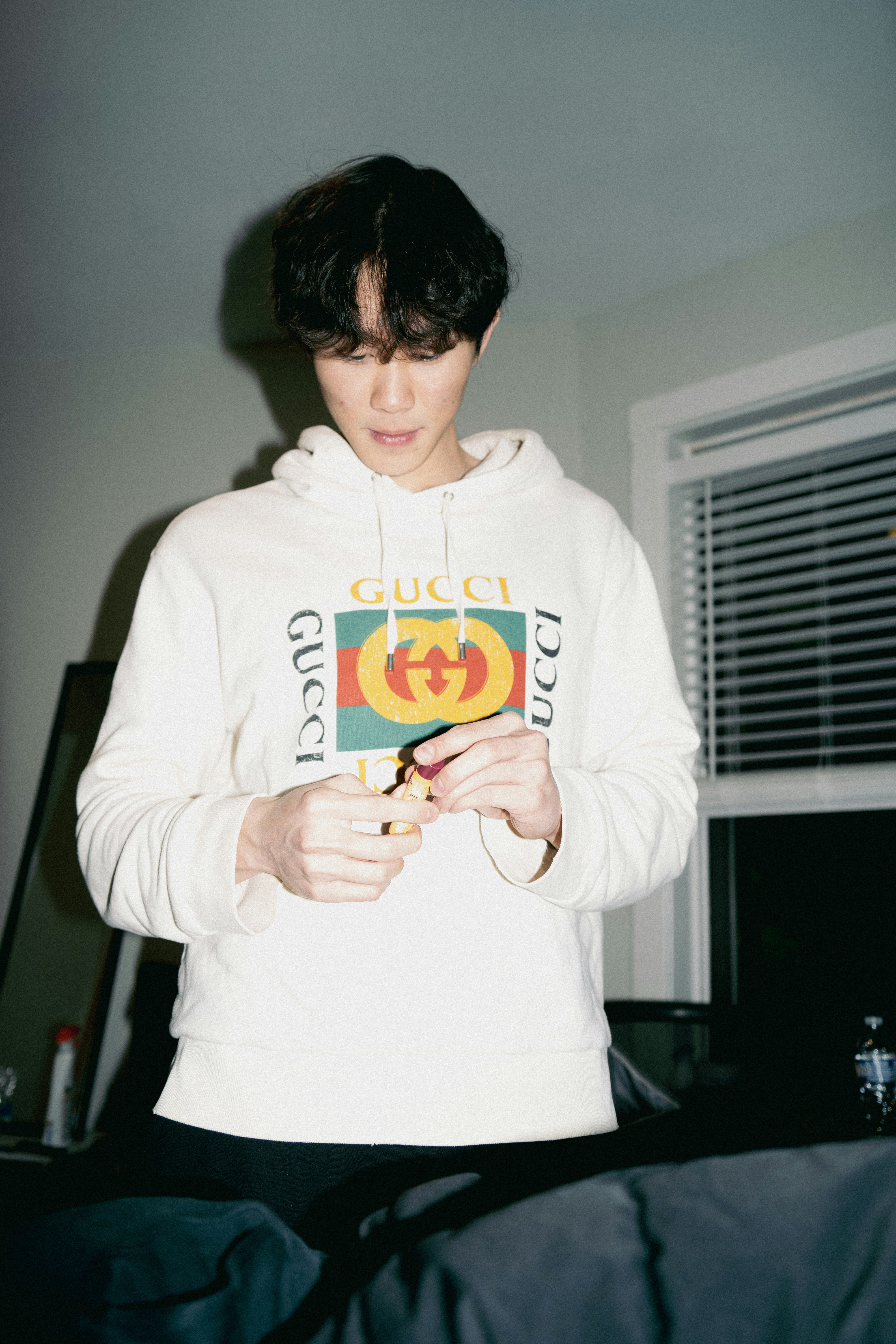 Young man in gucci hoodie holding a small object