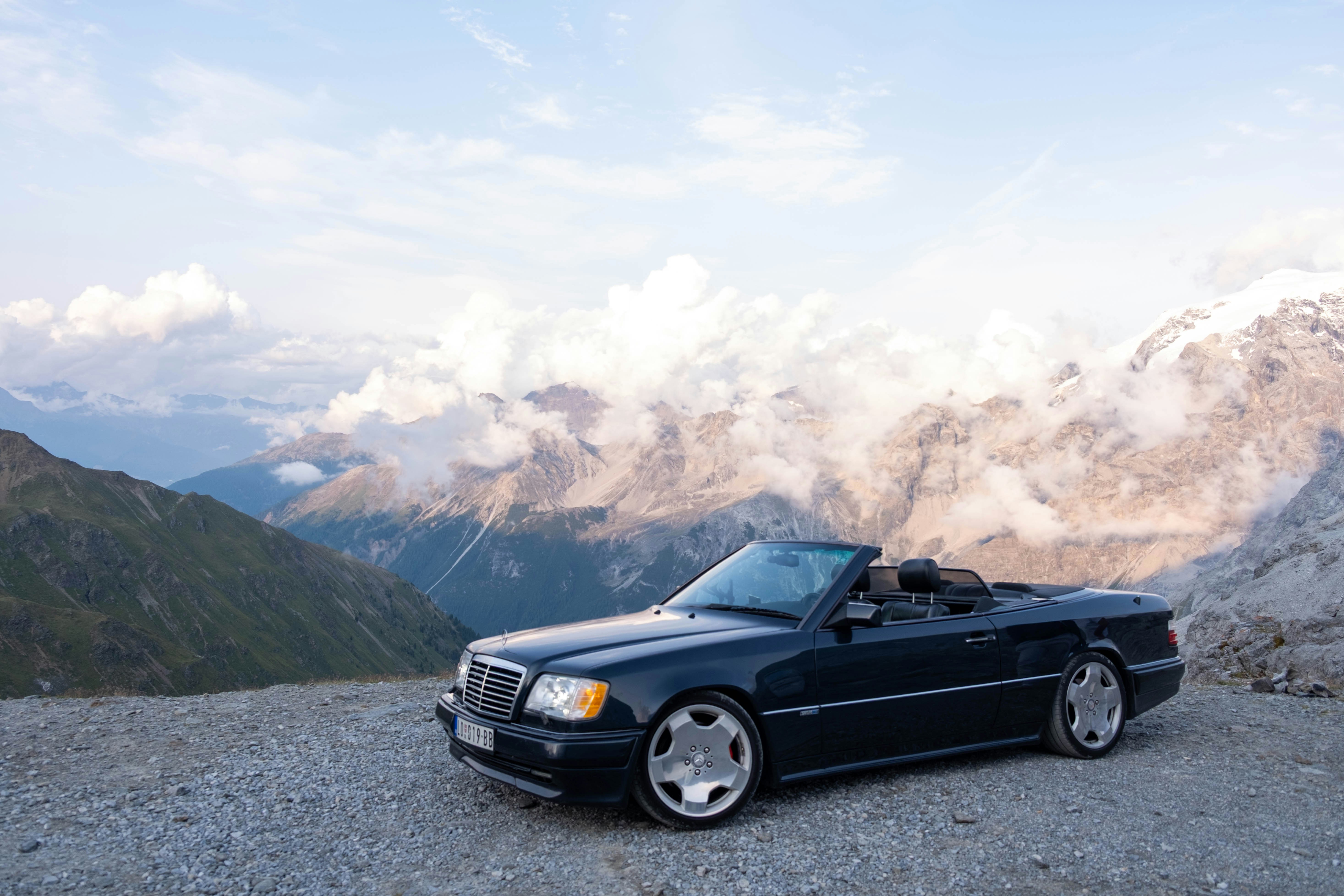 Dunkles Cabriolet, das auf einem felsigen Bergblick geparkt ist.