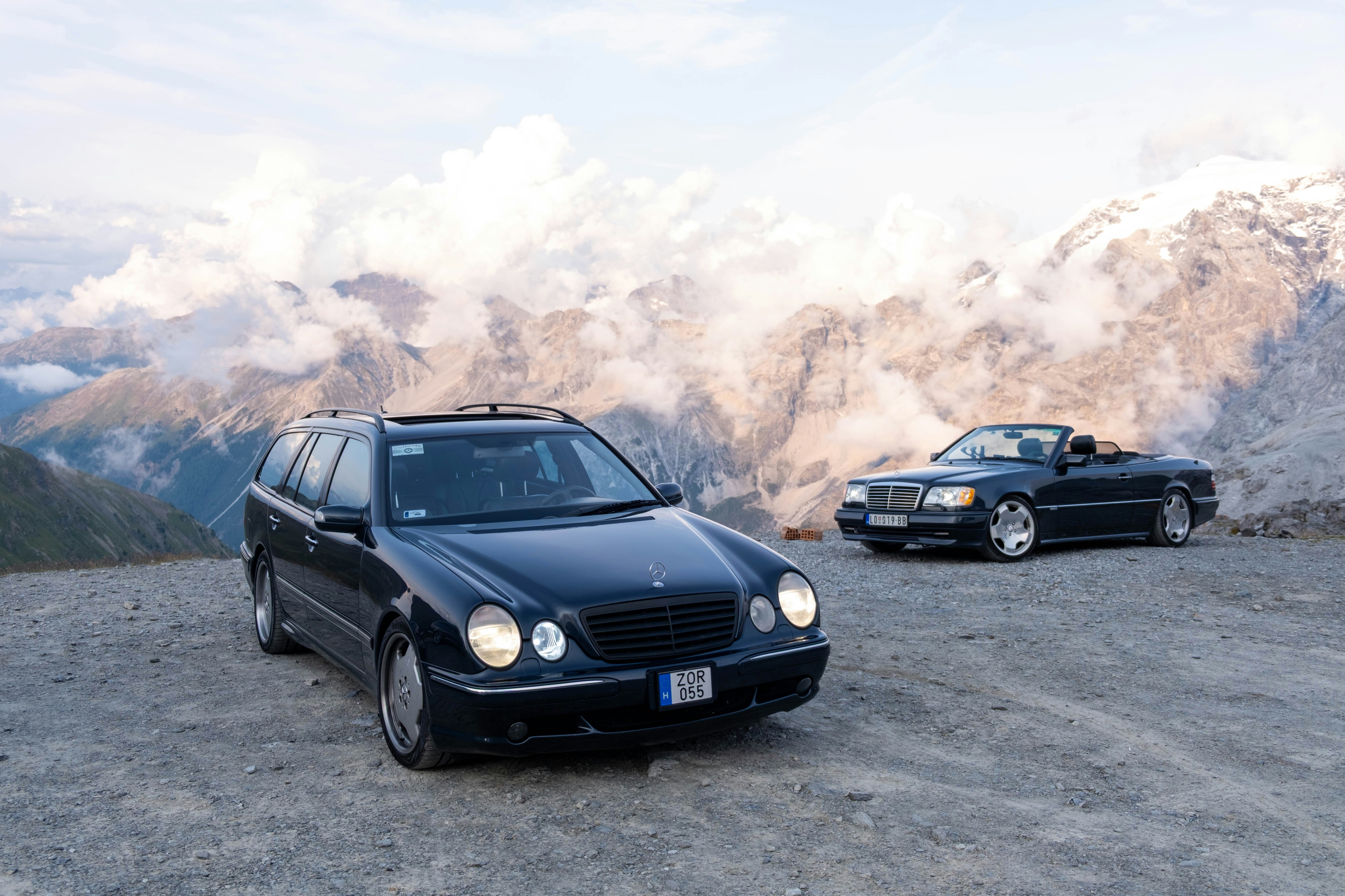 Zwei schwarze Mercedes-Benz parken auf einer Bergstraße.