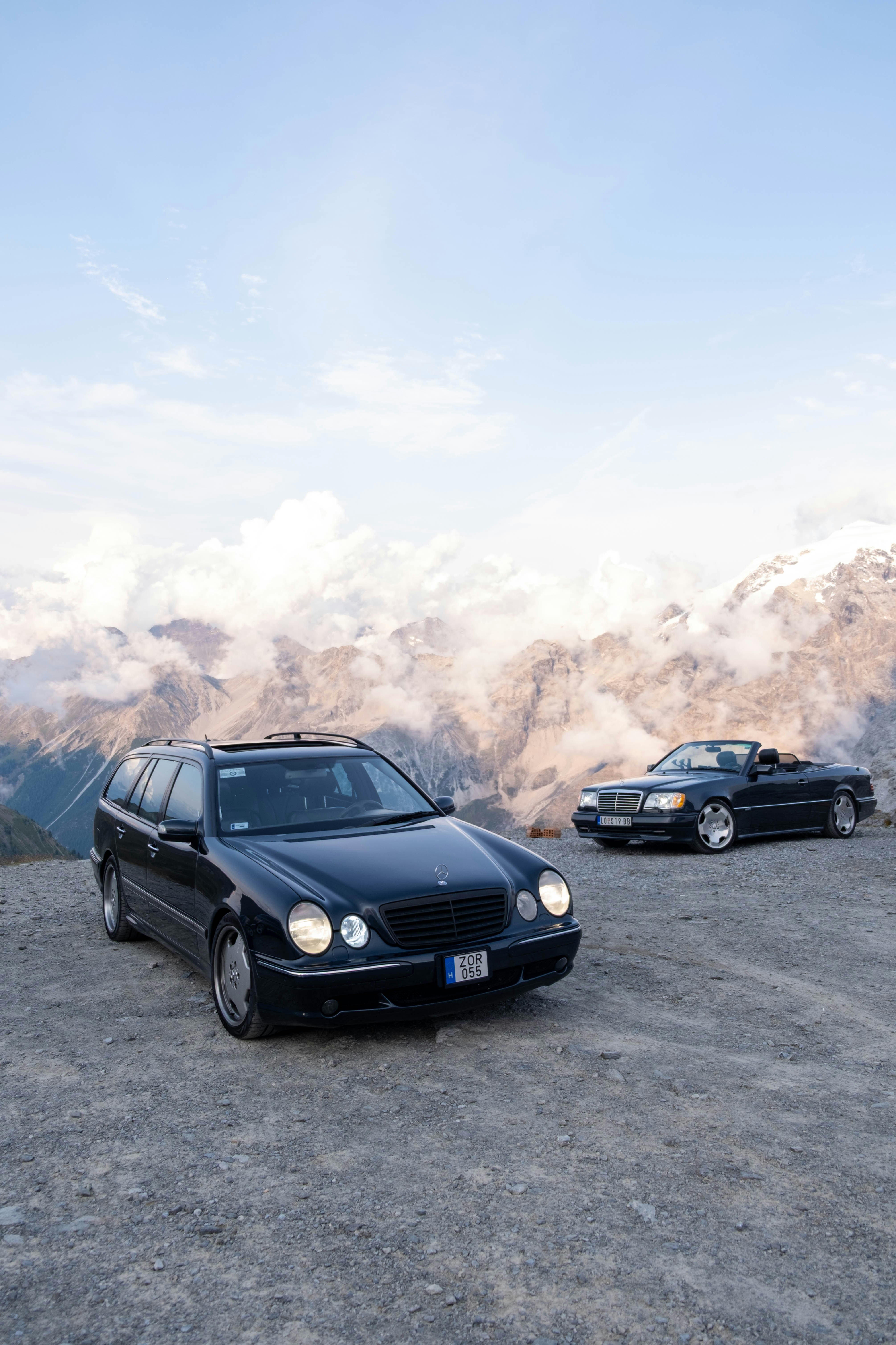 Zwei schwarze Autos, die auf einem felsigen Bergblick geparkt sind.