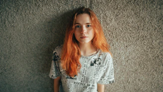 Young woman with long red hair against textured wall